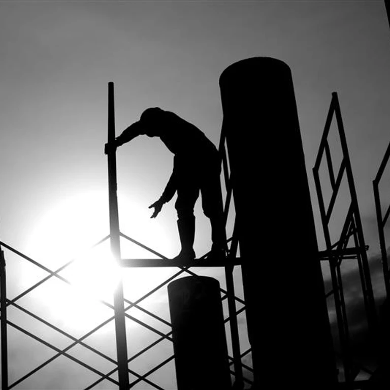 Image of a worker on scaffolding that is backlit