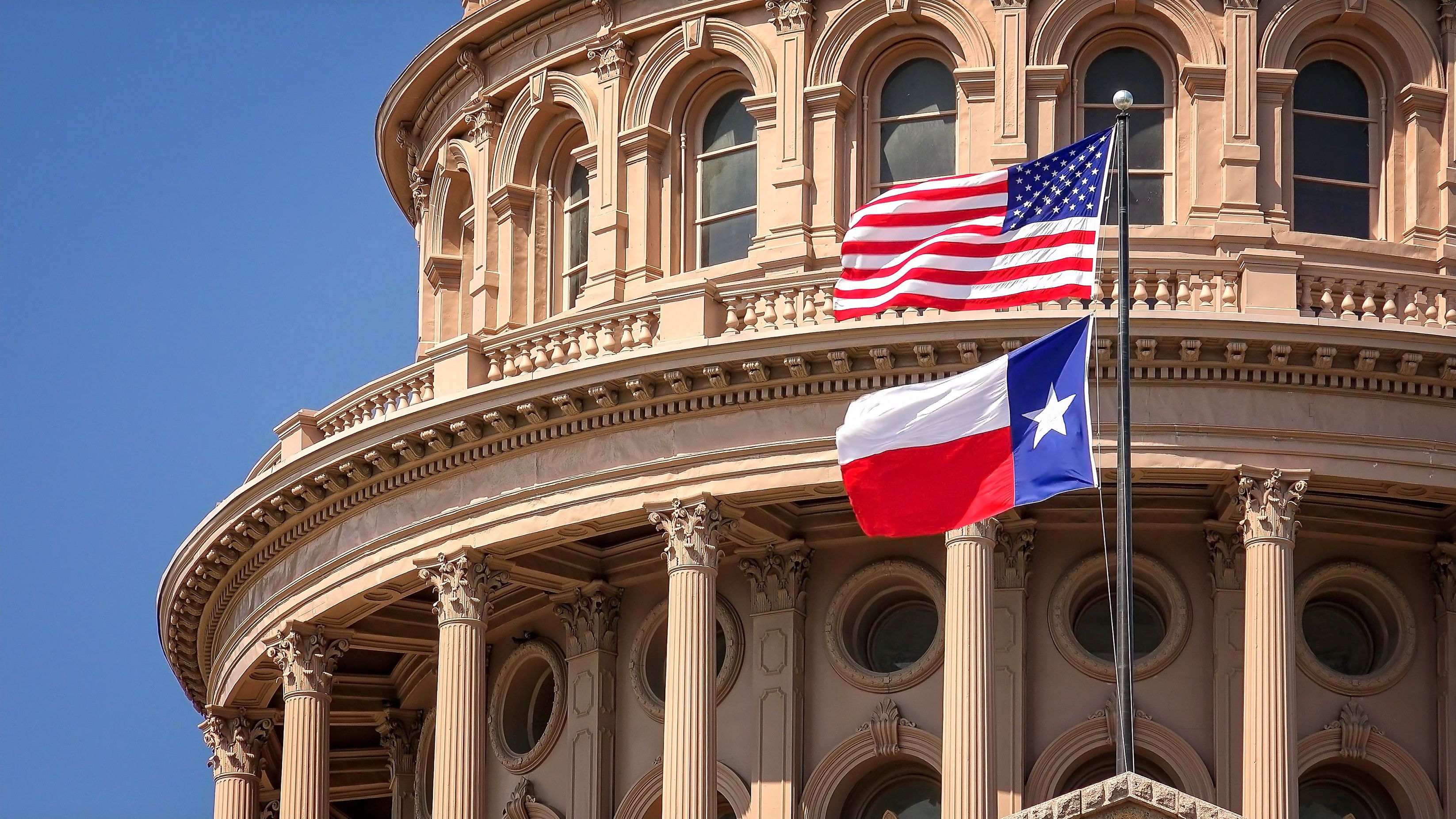 Image of the Texas and America flags outside of a governement building