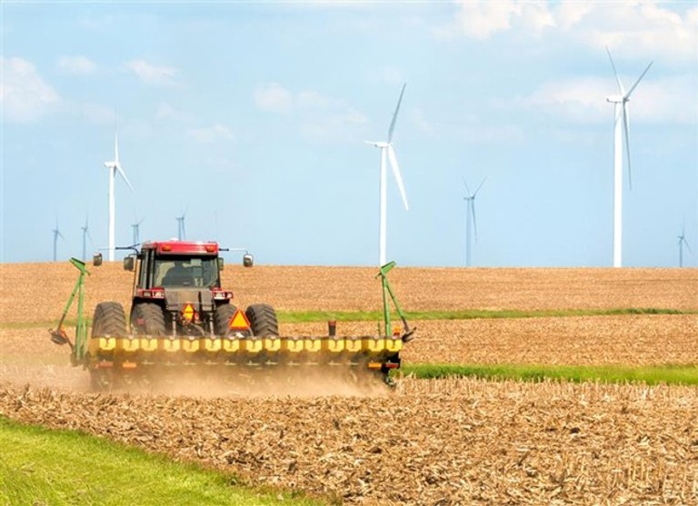 Image of a farmer seeding soybeans near a wind farm