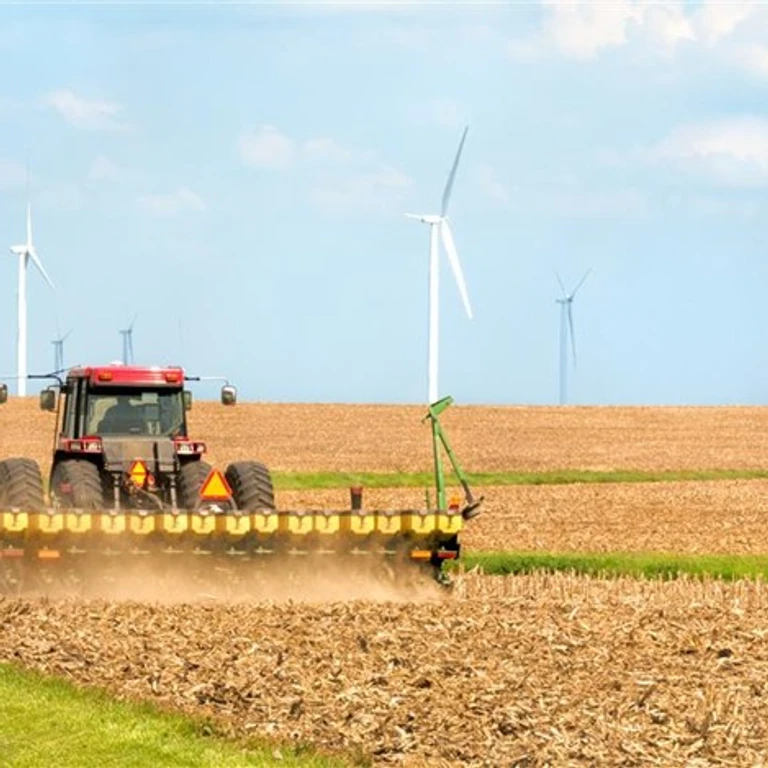 Image of a farmer seeding soybeans near a wind farm