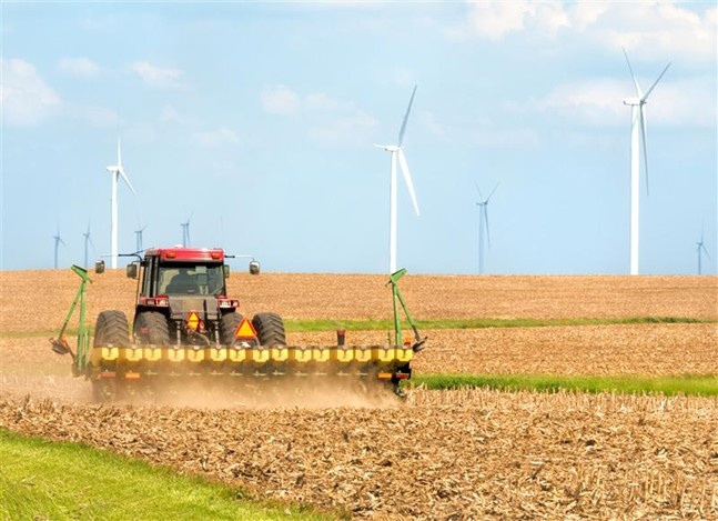Image of a farmer seeding soybeans near a wind farm