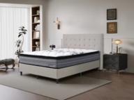 Dreamland Omega Medium mattress, queen size, angled view in a styled bedroom.