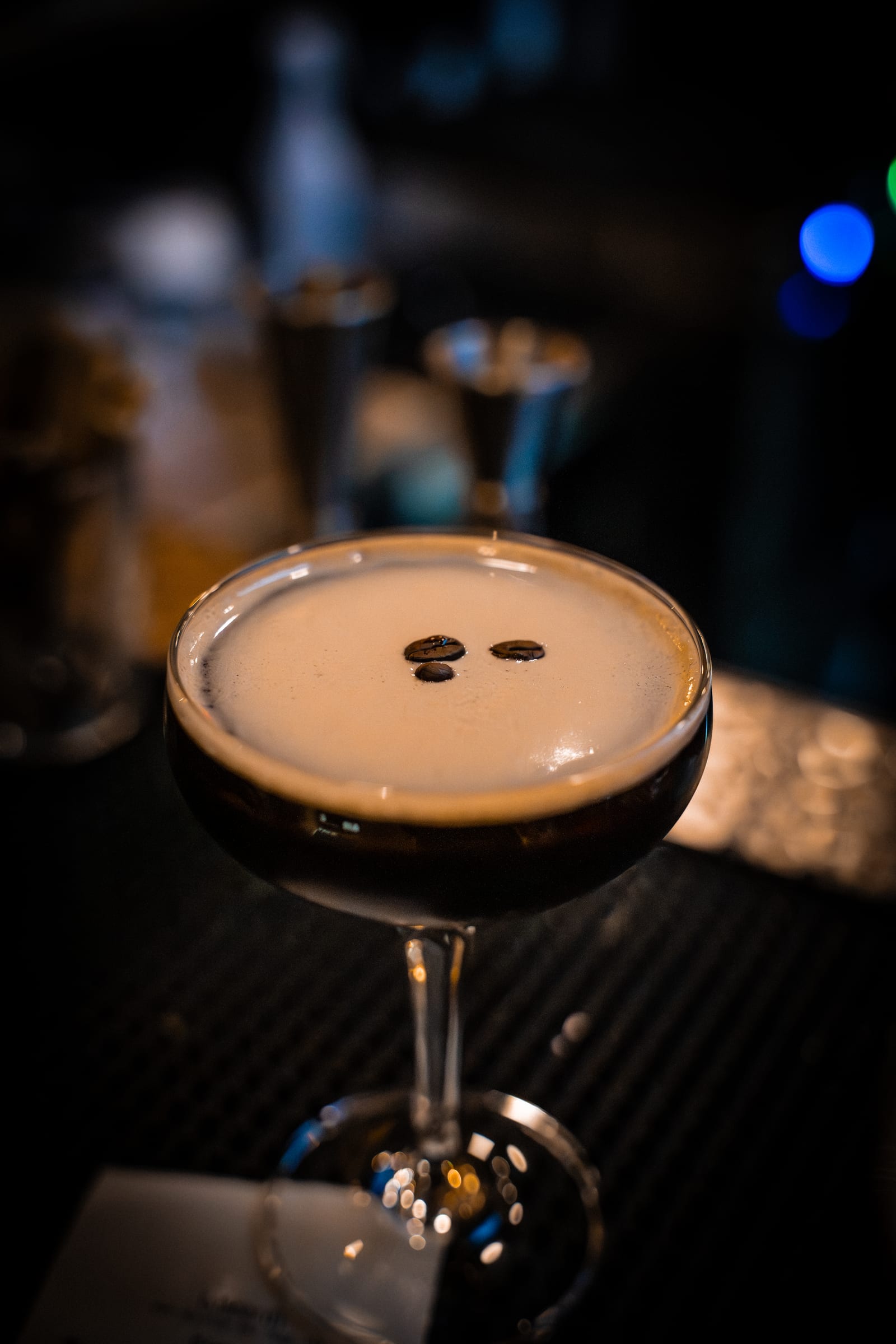An espresso martini topped with three coffee beans at the bar