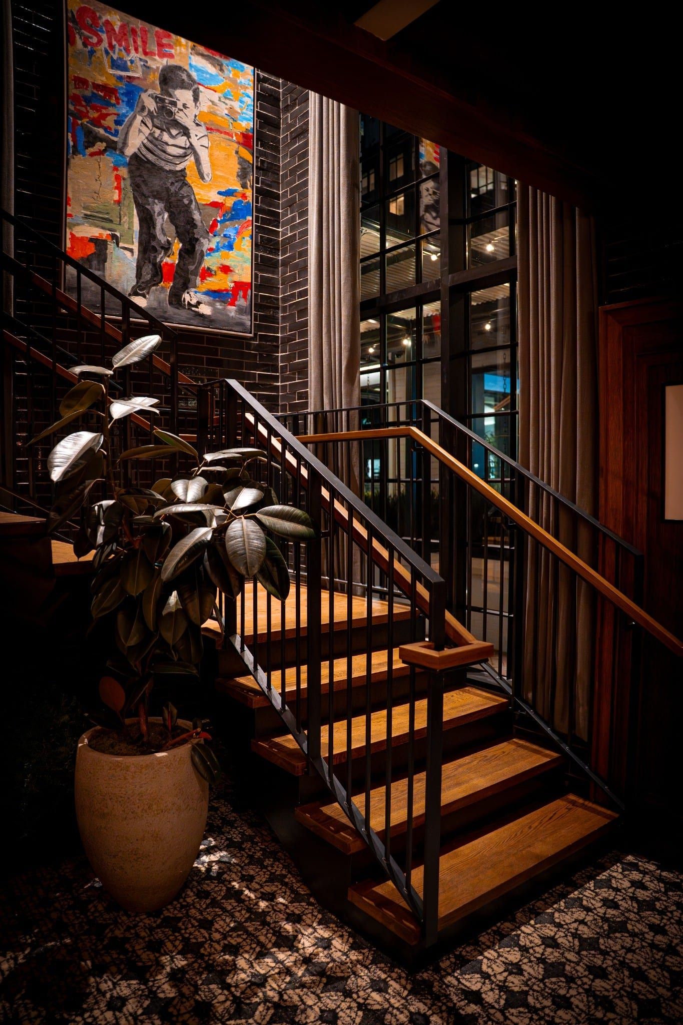 Wooden staircase with black railings beneath a colorful abstract painting
