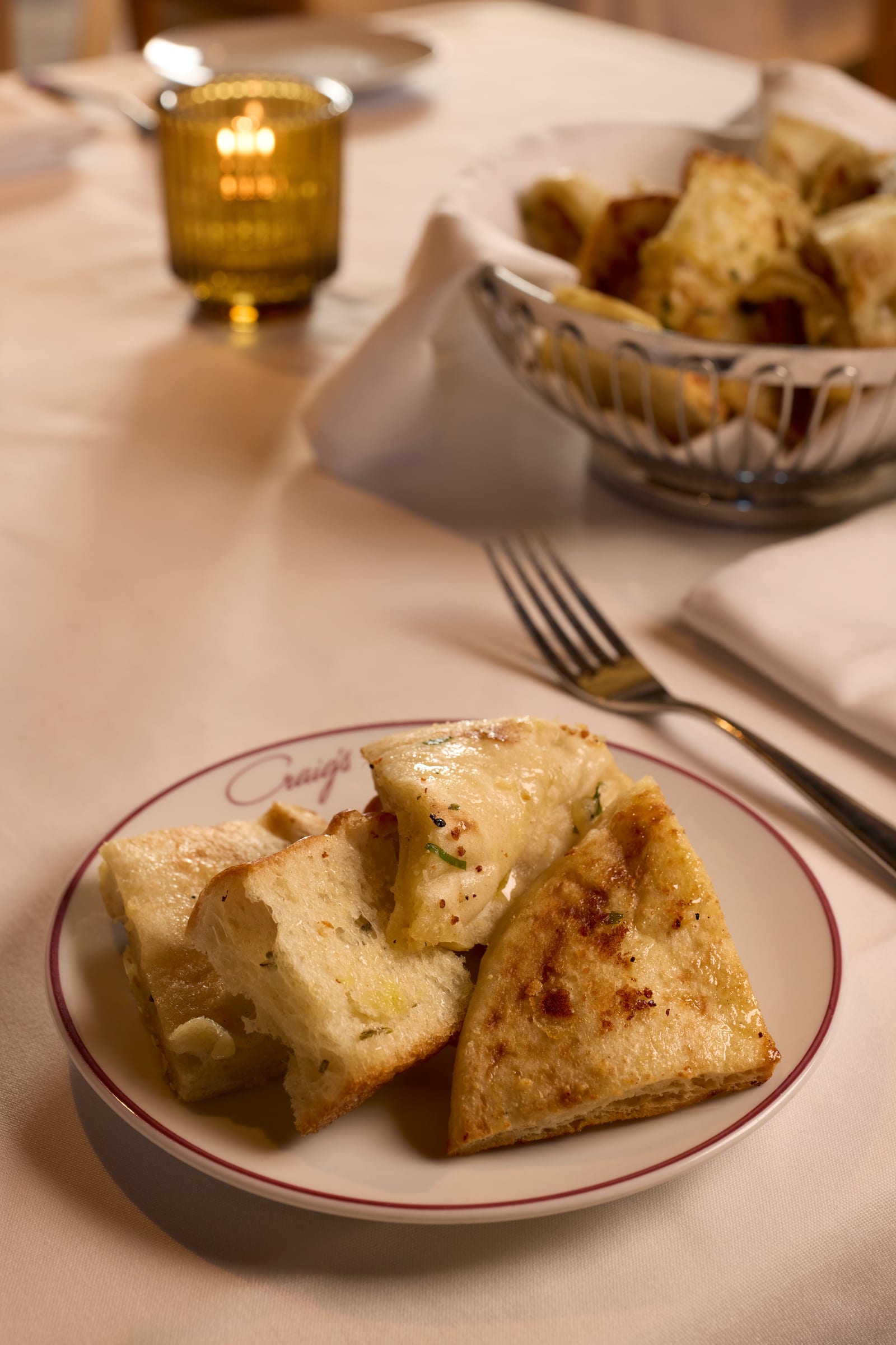 Buttered toast points plated beside a bread basket on a white tablecloth