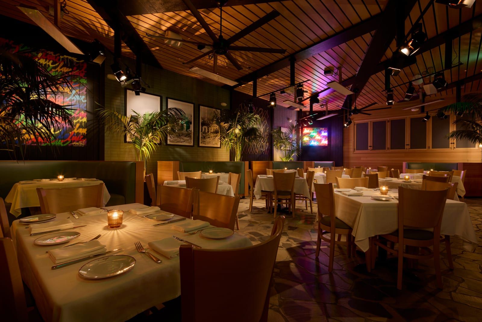 Palm-lined dining room with cane ceiling fans and candlelit tables