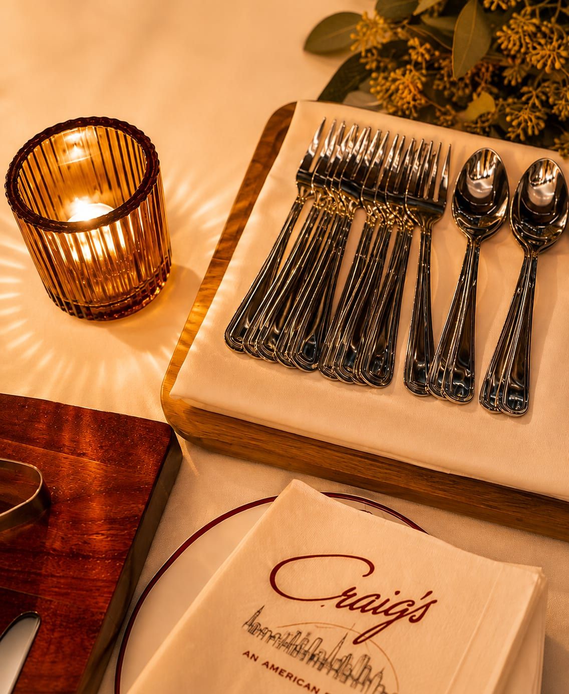 Polished flatware and a Craig's napkin laid out by candlelight
