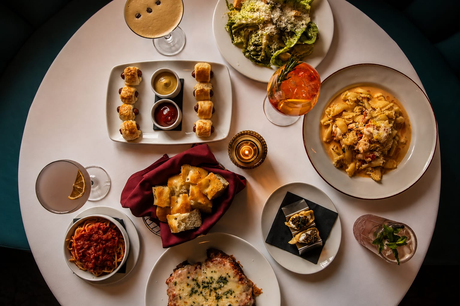 Overhead spread of Craig's dishes — pigs in a blanket, salads, pastas, and garlic bread