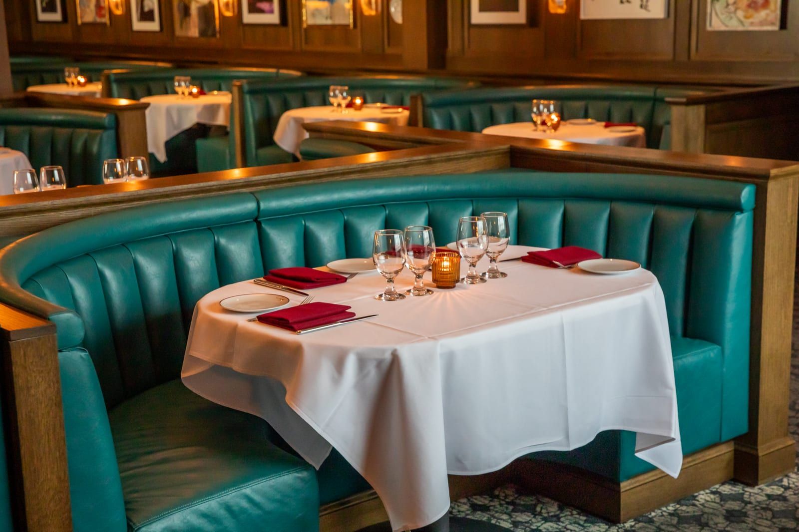 Teal leather booth with a white-clothed table set with wine glasses
