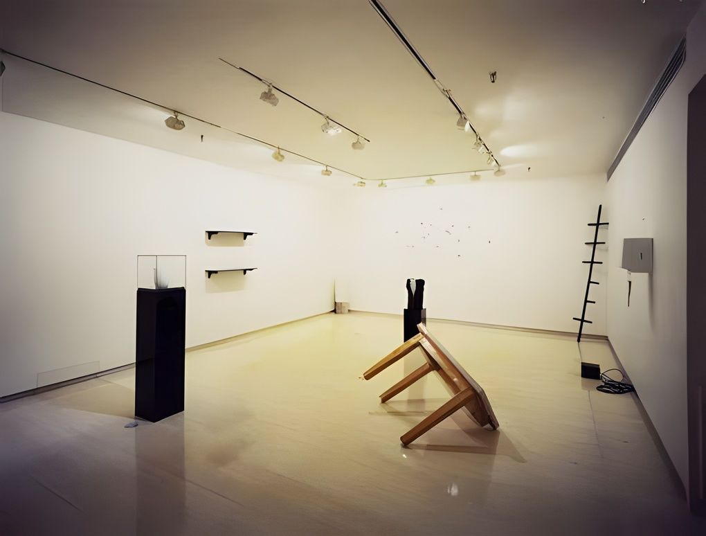 Vik Muniz, installation view at Stux Gallery, 1988: a sparse white room with a pedestal vitrine, wall shelves and an overturned wooden chair.