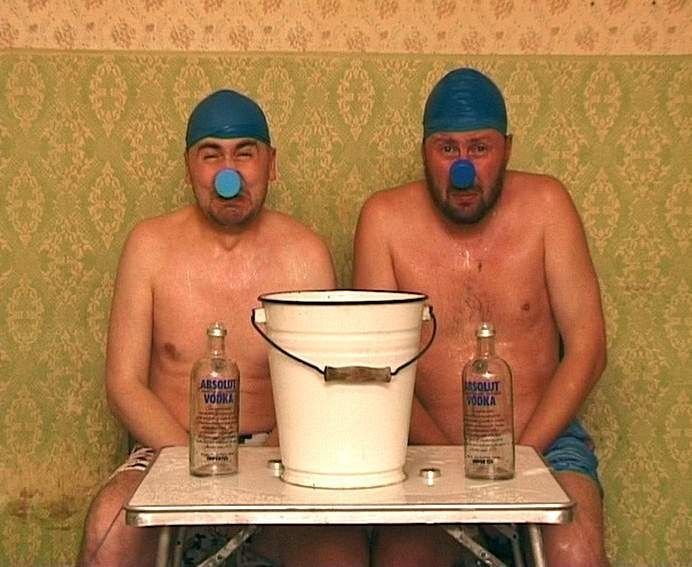 Blue Noses, photograph: two shirtless men in swimming caps and masks sitting at a table with a bucket and bottles.