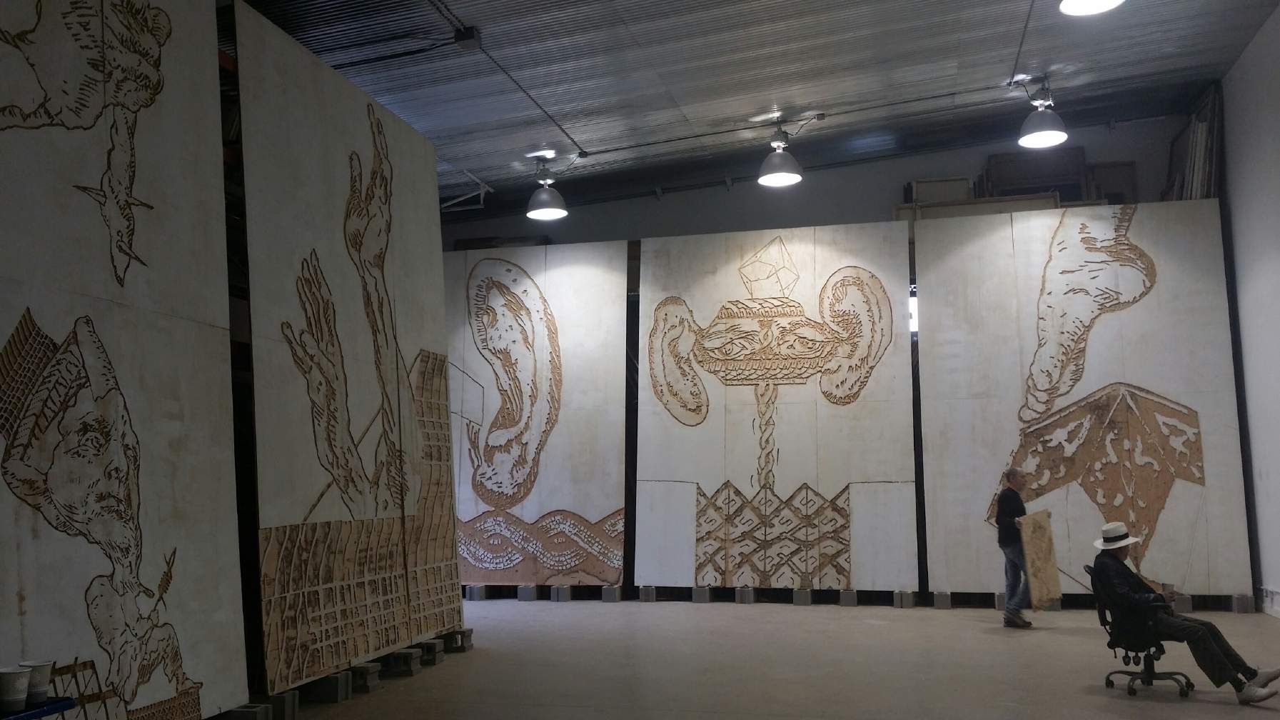 Michael Zansky, studio installation view, 2015: large panels with carved, swirling relief imagery standing in a wide room.