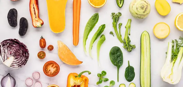 Värikkäitä raakoja kasviksia marmorilla: varsiparsakaali, porkkana, kurpitsa, kurkku, fenkoli ja paprika