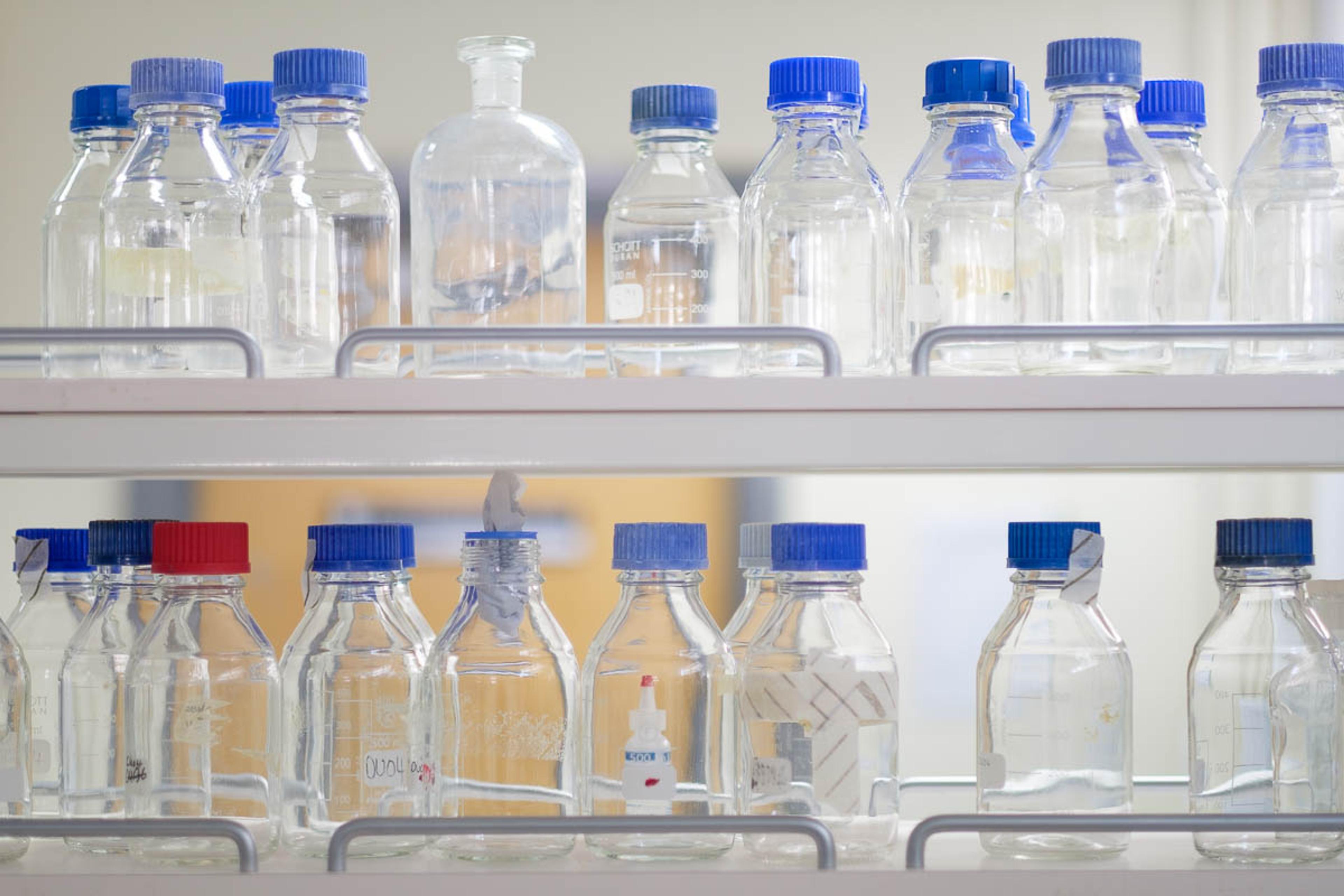 Glass bottles arranged on a laboratory shelf.