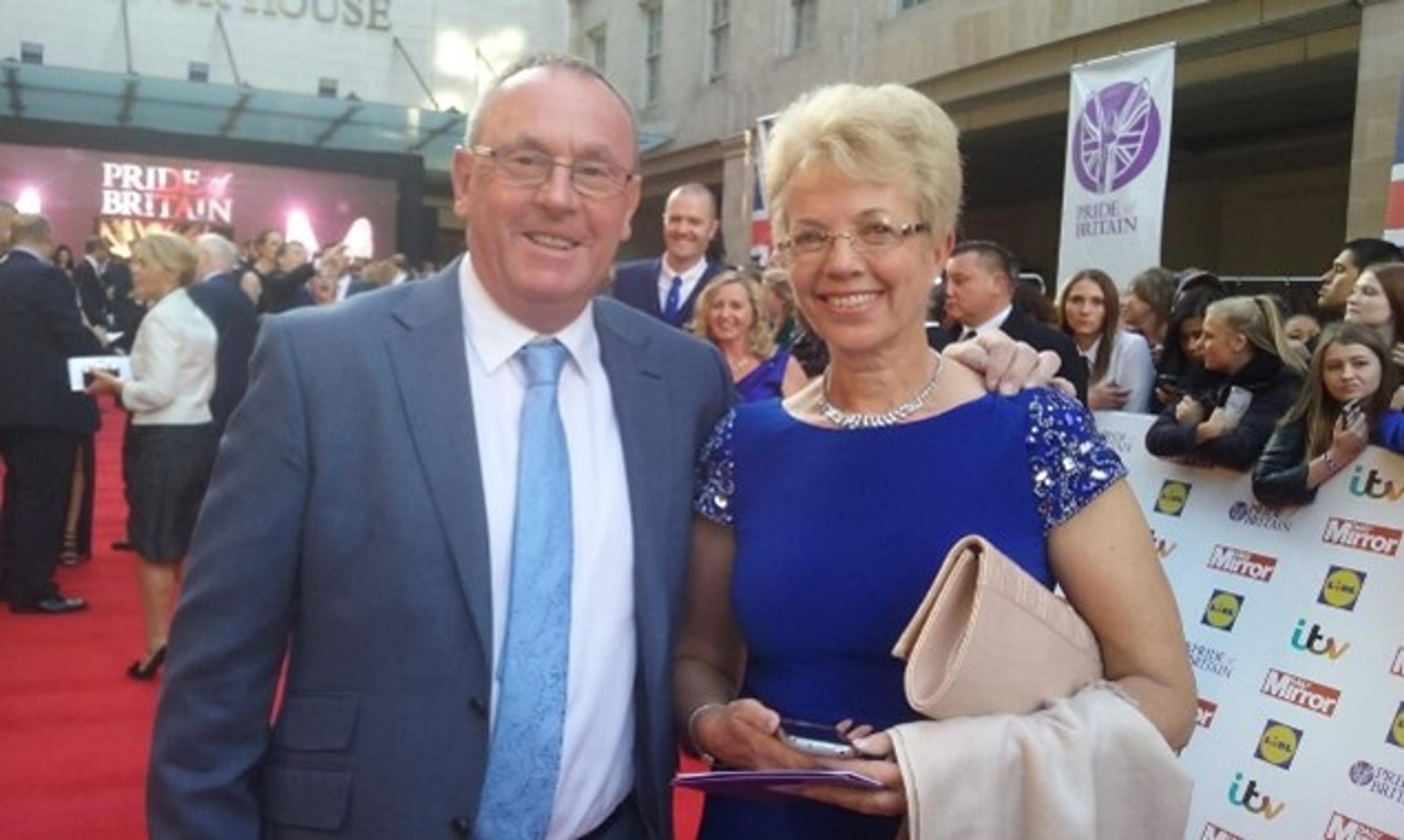 John Price, a patron of Weston Park Cancer Charity, and his wife, Anne Price, stand facing the camera in front of a crowd of people at the Pride of Britain Awards.