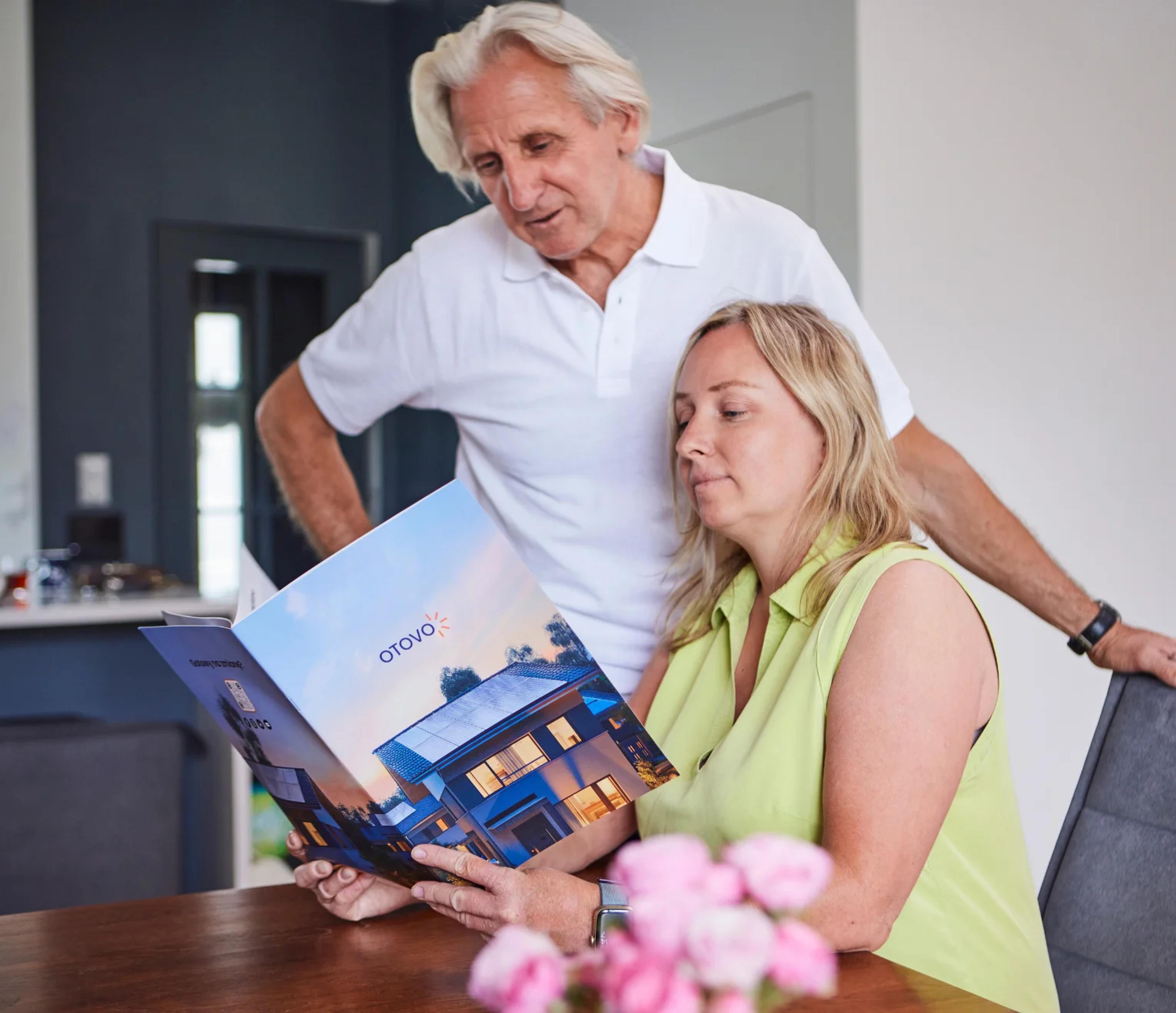 Mann und Frau schauen durch eine Otovo Broschüre