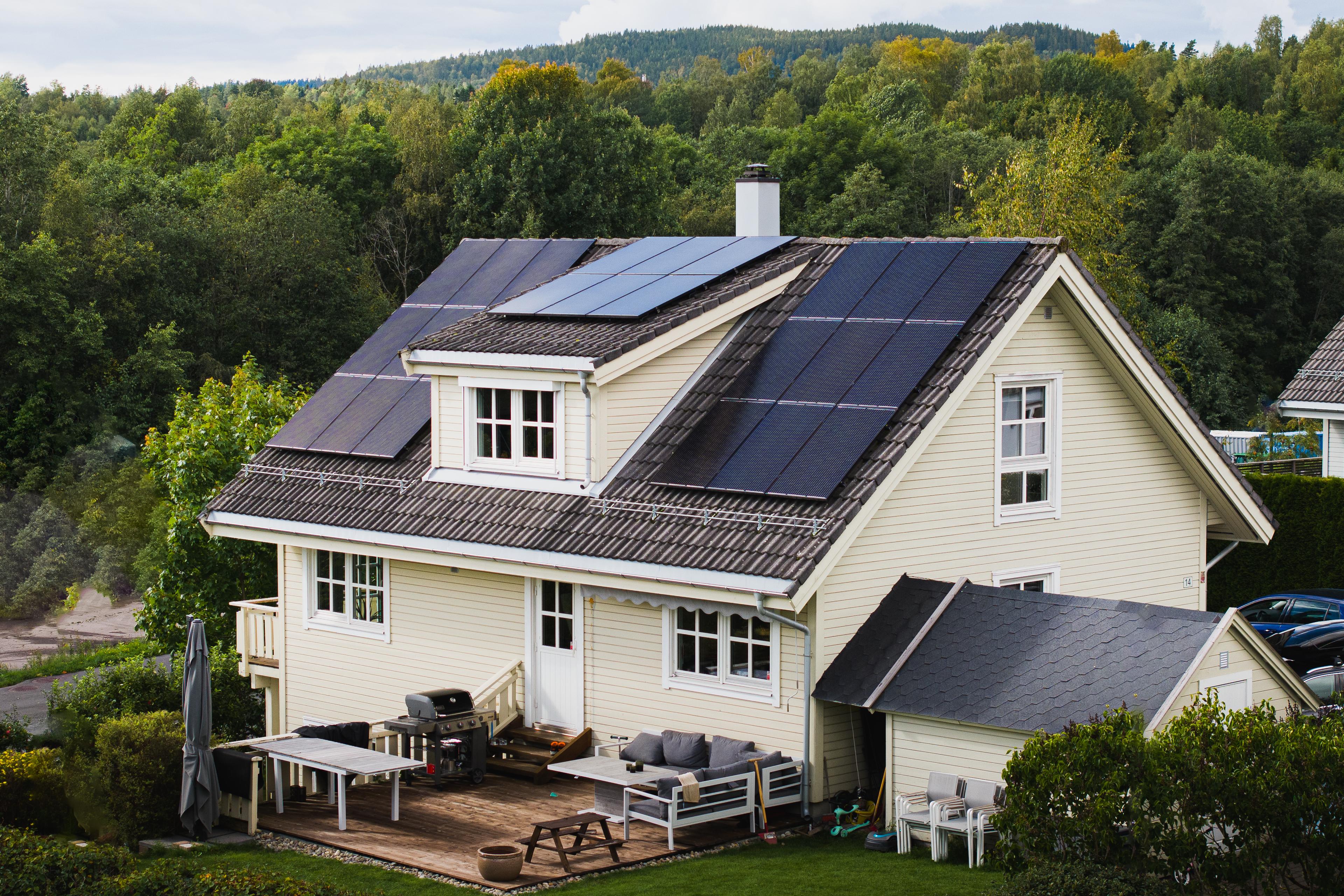 gult hus med monterte solcellepaneler