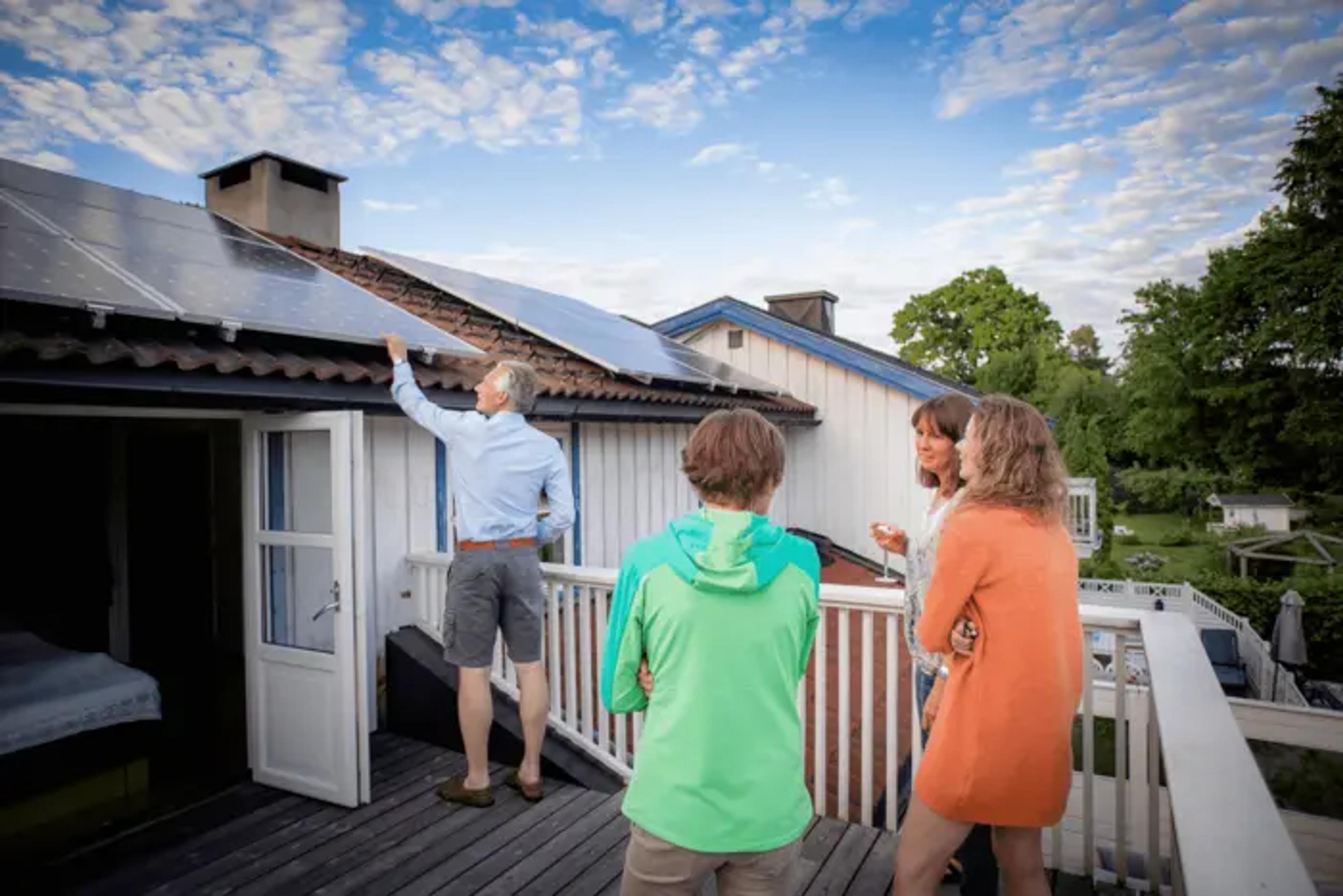 Familie steht vor einem Haus mit PV-Anlage