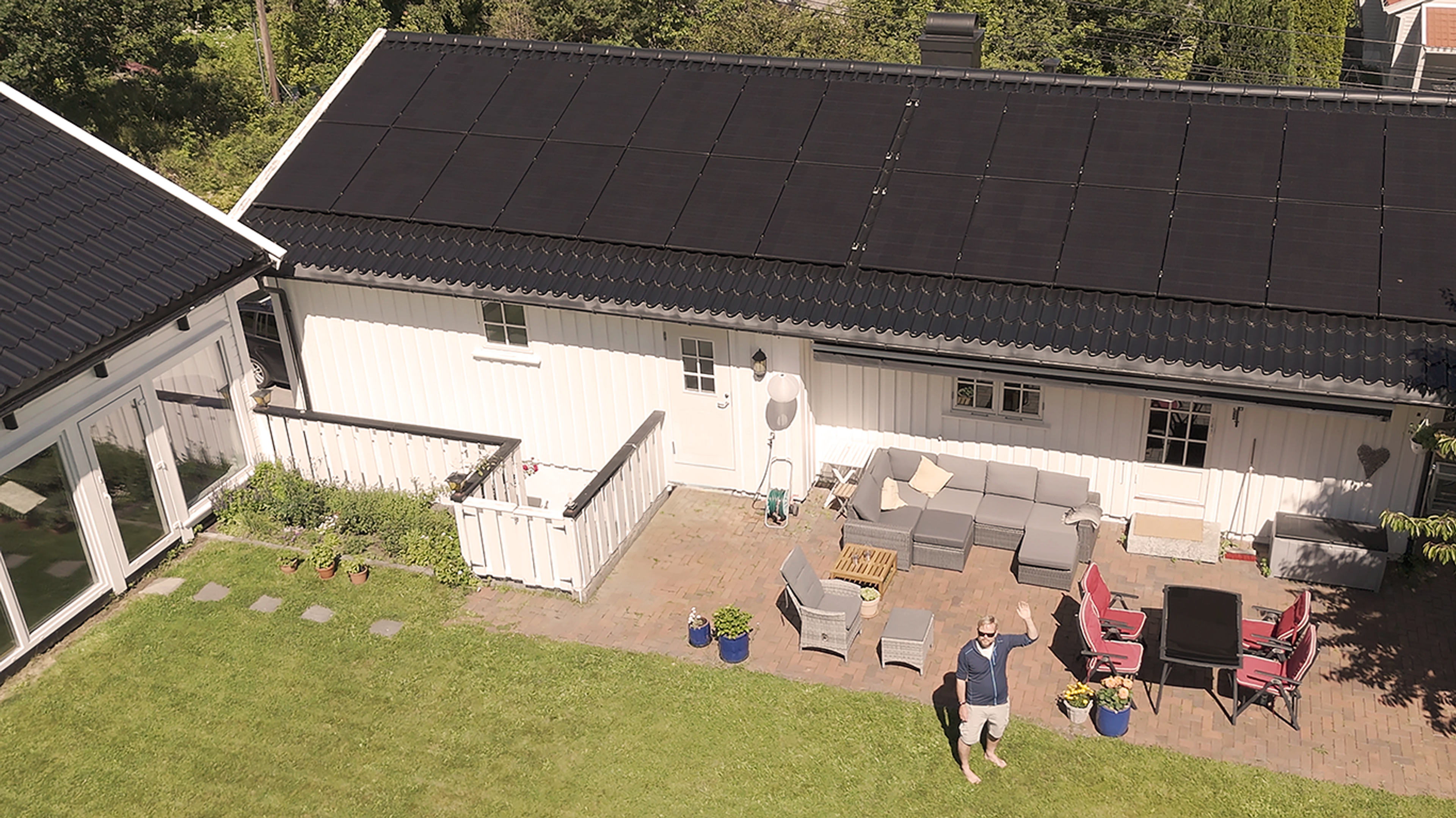 Mann vinker foran hus med solceller på taket