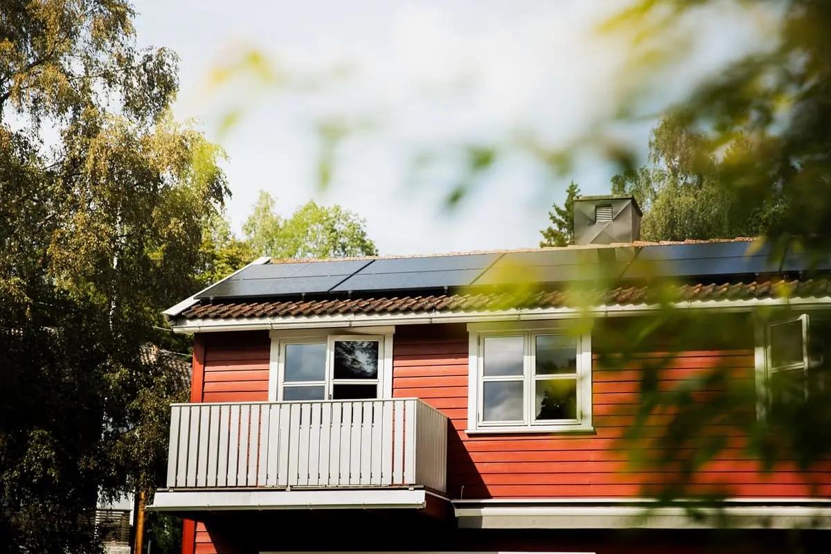 rött hus med balkong och solpaneler på taket