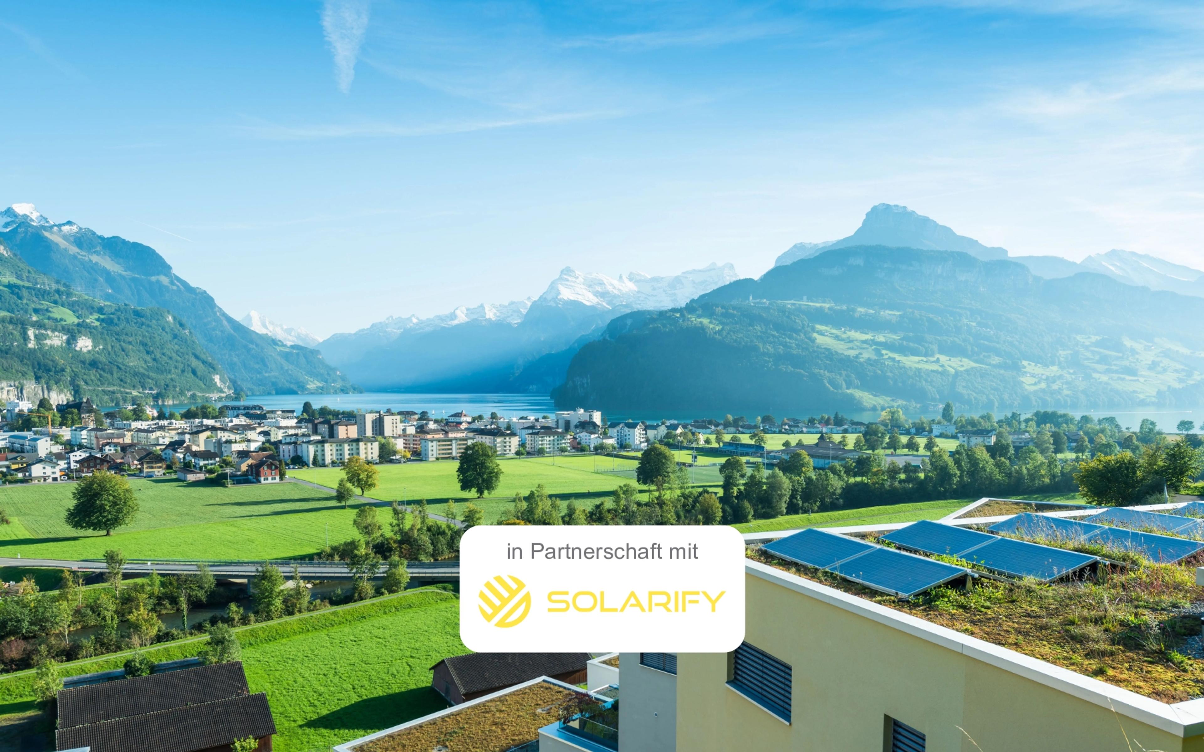 Gebäude mit Photovoltaikanlage mit schweizer Landschaft im Hintergrund