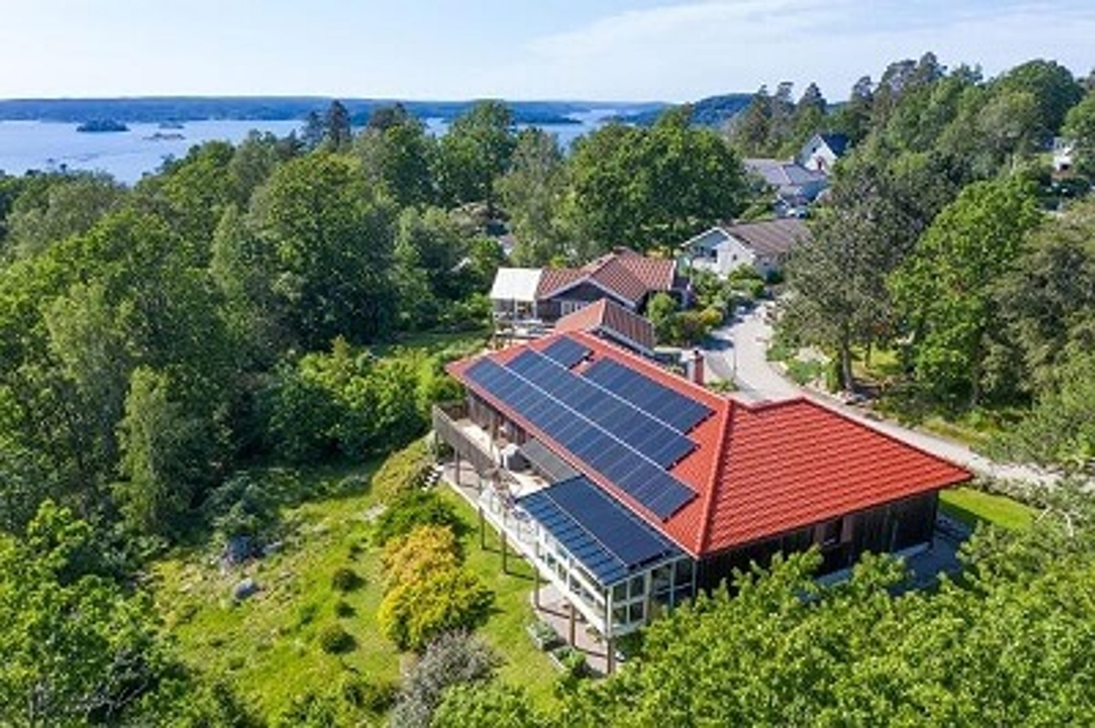 villa med solcellepaneler i frodig landskap