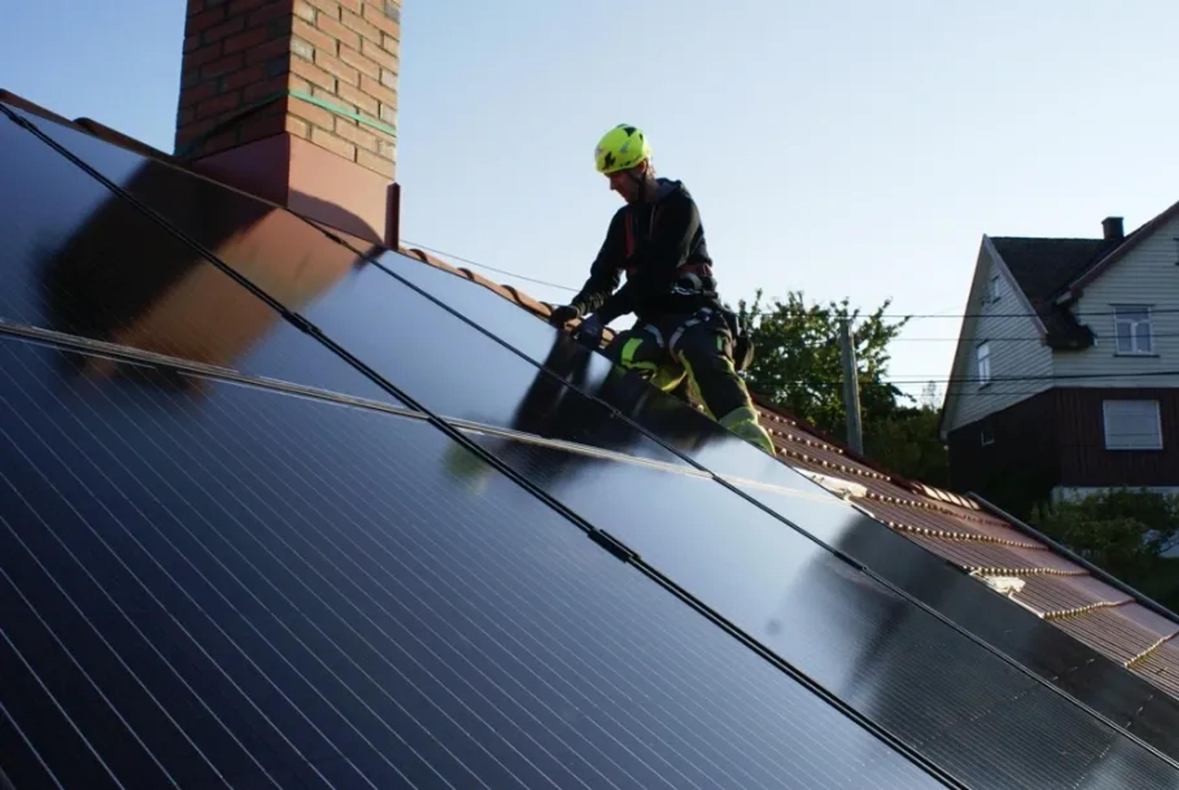Installateur auf Dach mit PV-Anlage
