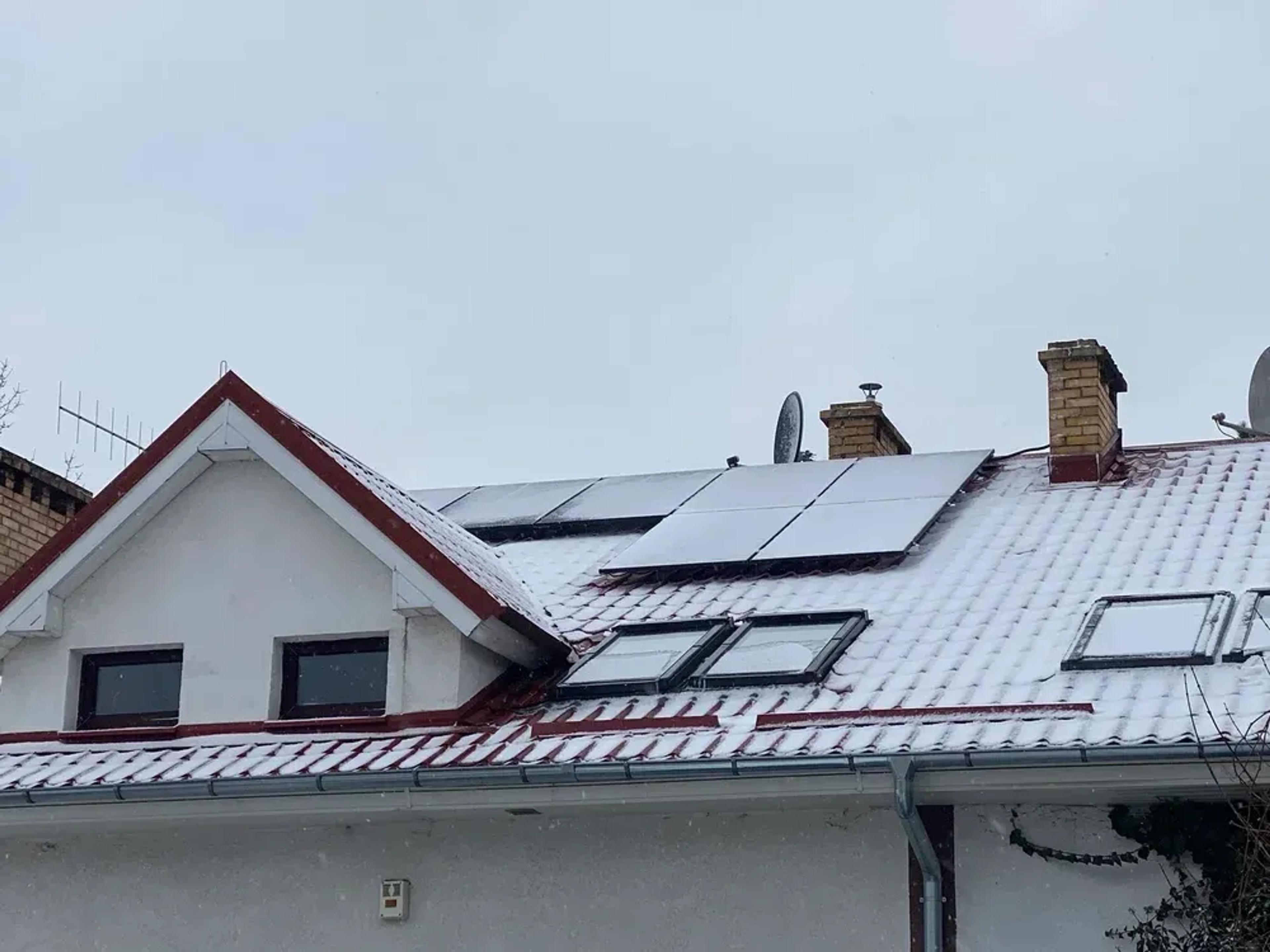 Haus mit Solaranlage, die mit Schnee bedeckt sind