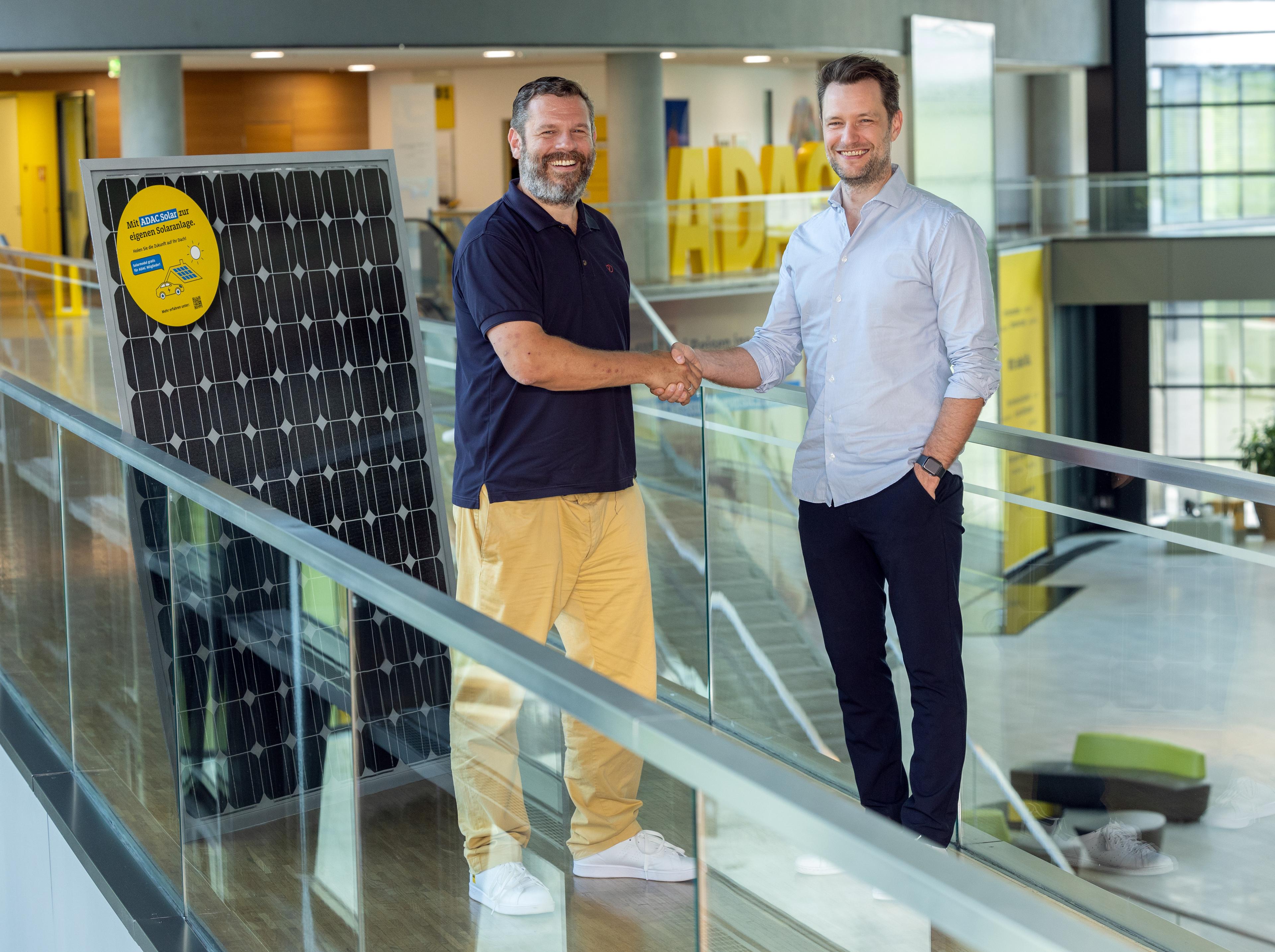 Sascha and Artur shaking hands next to pv panel