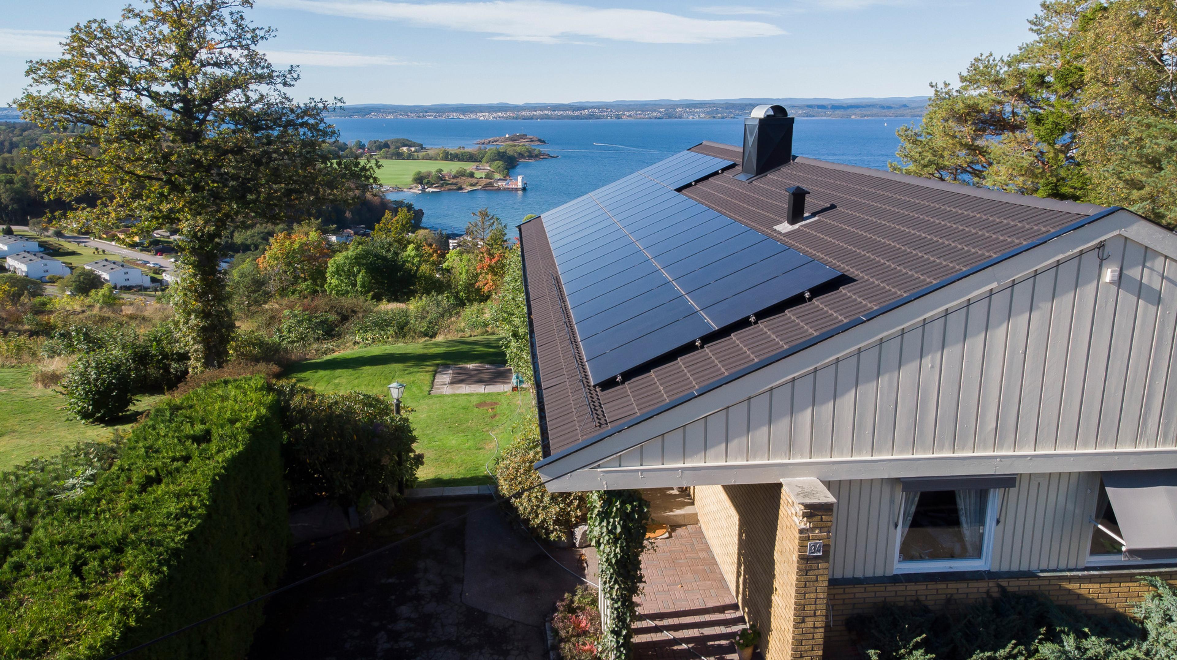 hus vid vattnet med solceller på taket