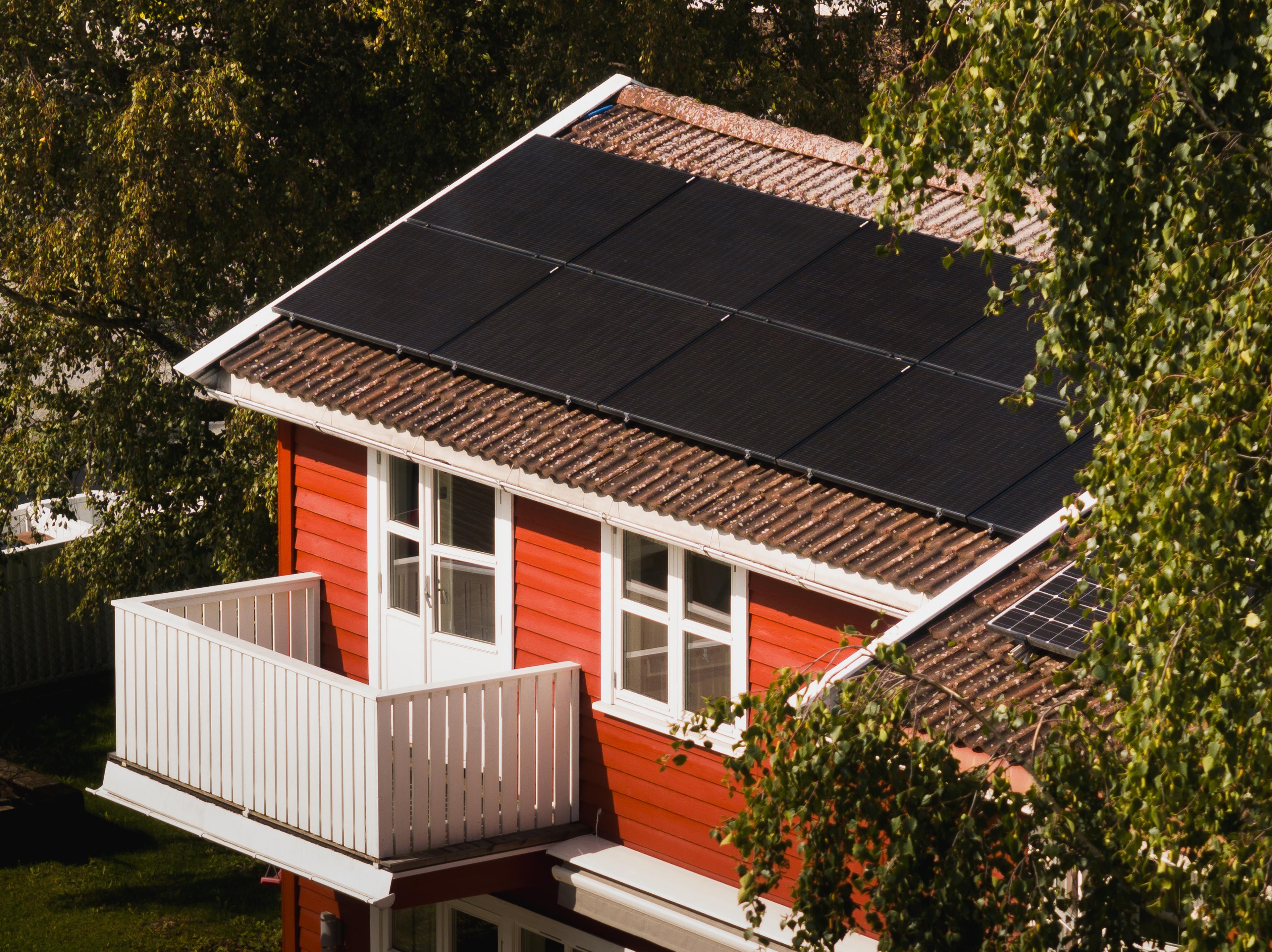 rødt hus med solcellepaneler på taket