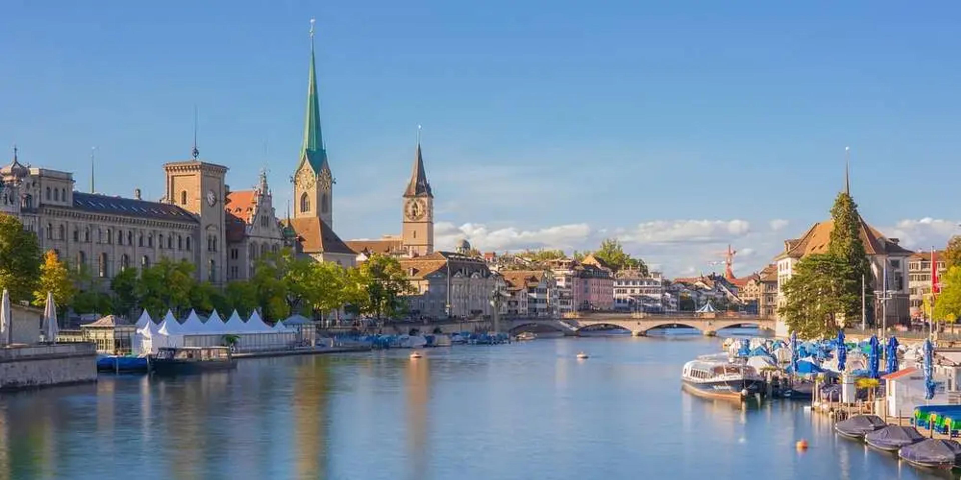 Blick auf die Stadt Zürich mit Fluss und Booten im Vordergrund