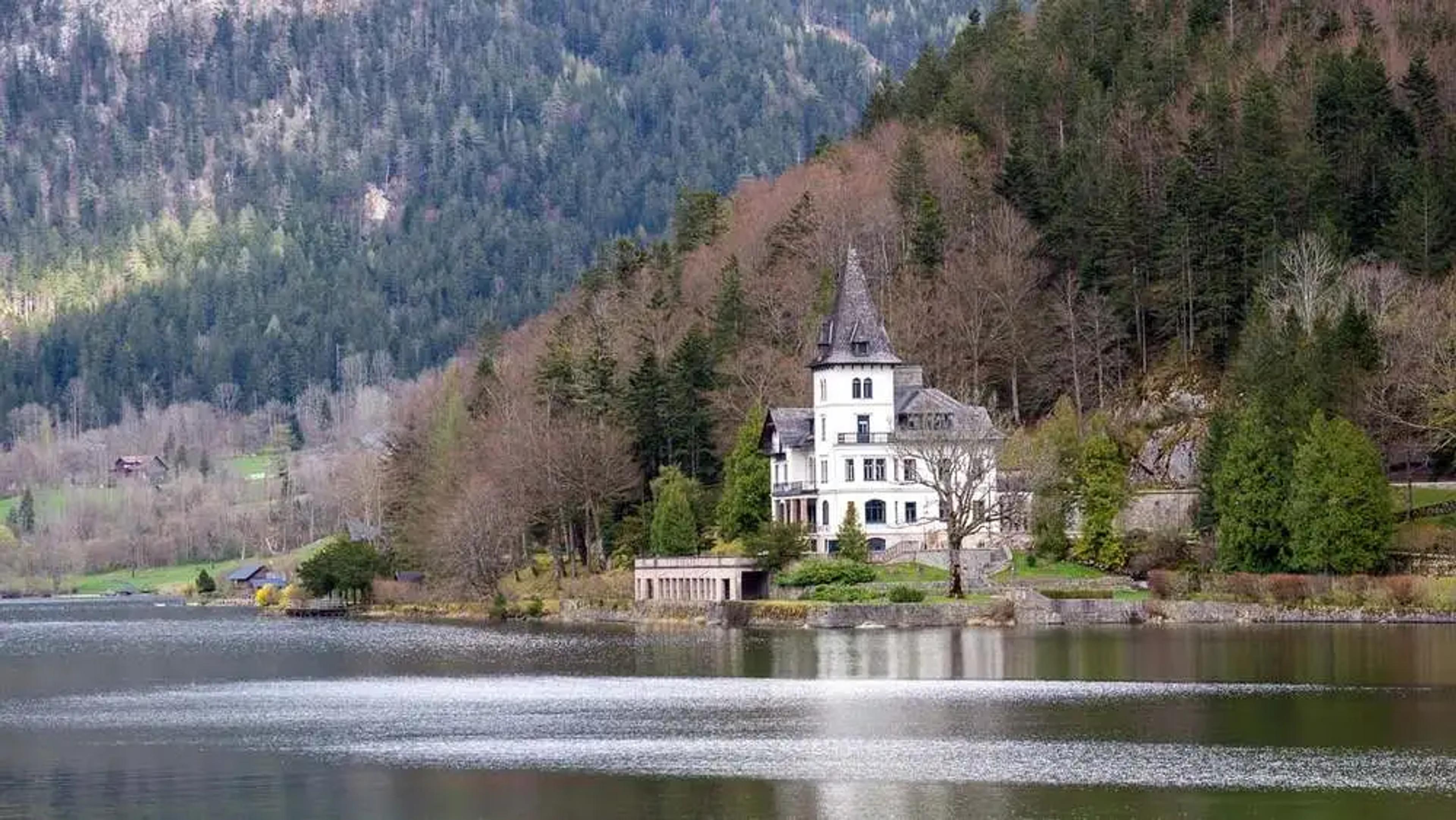 Schloss in der Steiermark mit Bergen im Hintergrund und See im Vordergrund