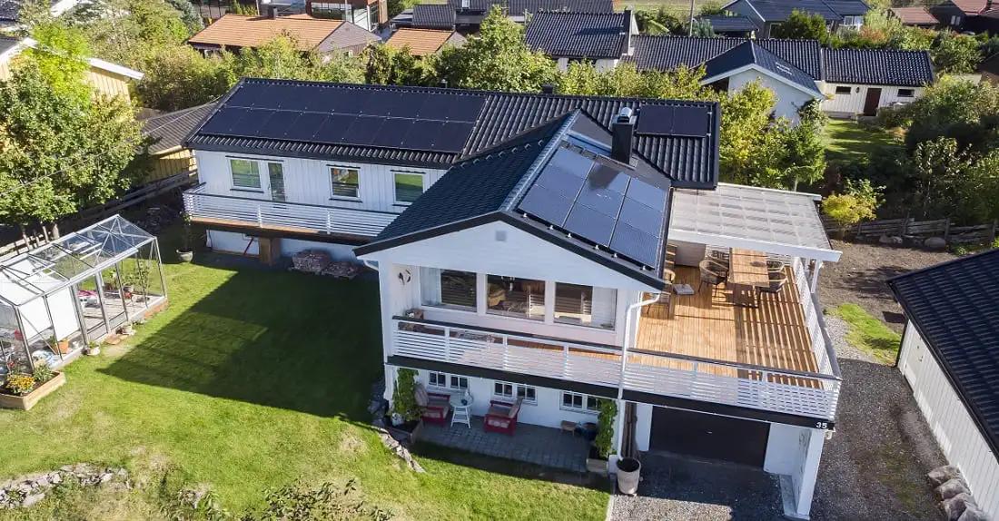 vy över stort vitt hus med svarta solceller på taket