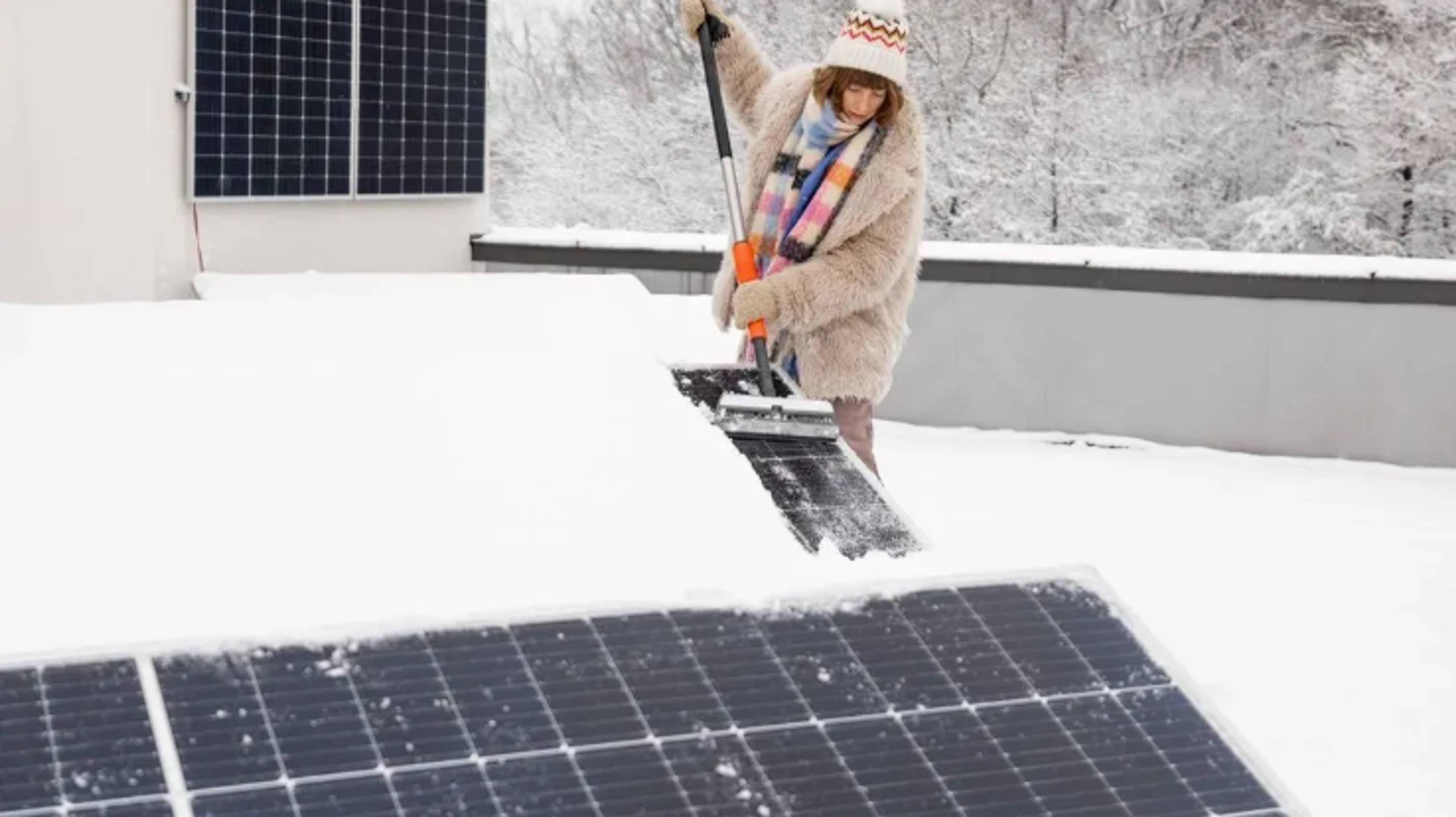 person cleaning snow from panels 