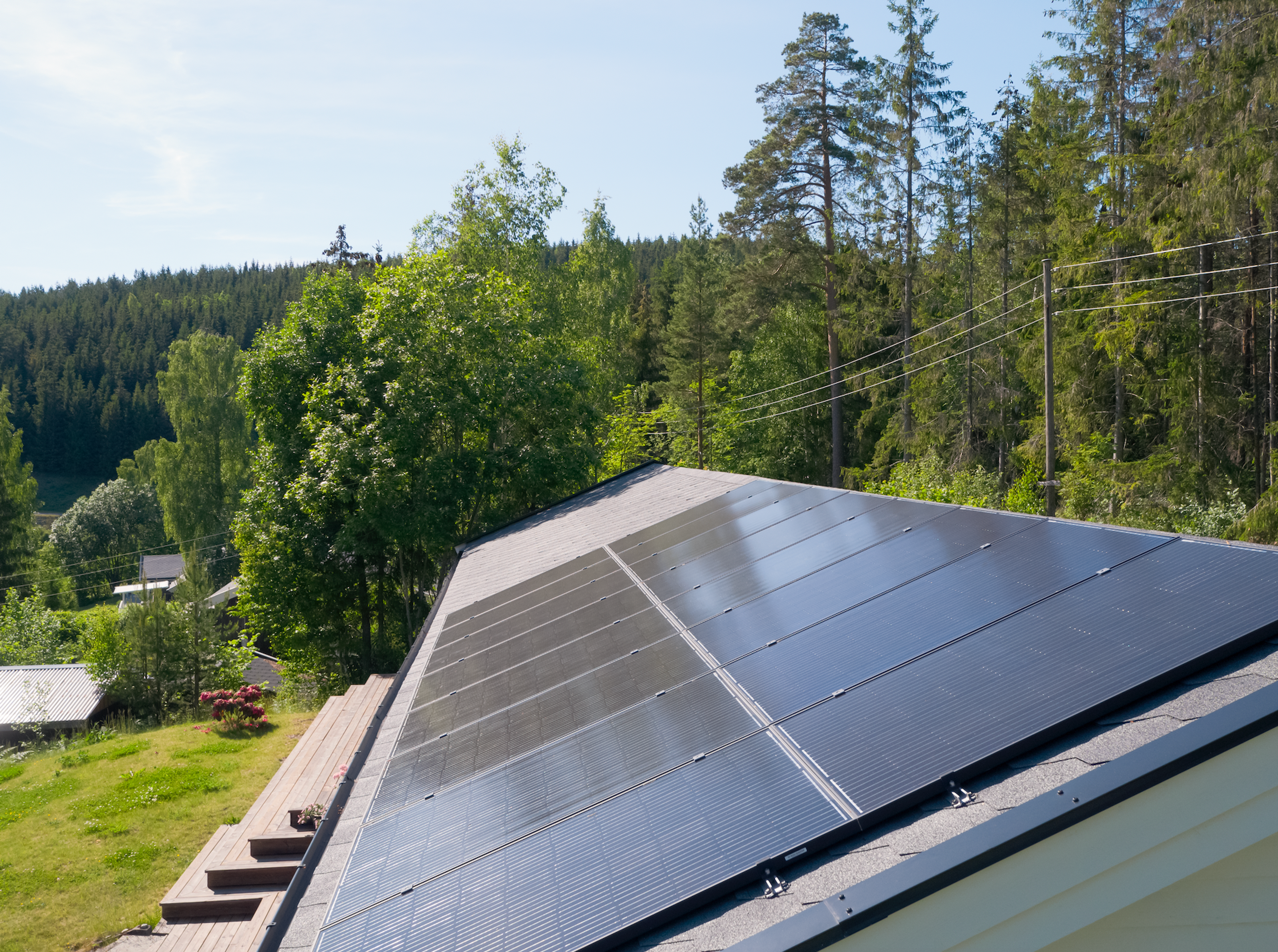 tak med solcellepanel i et frodig landskap