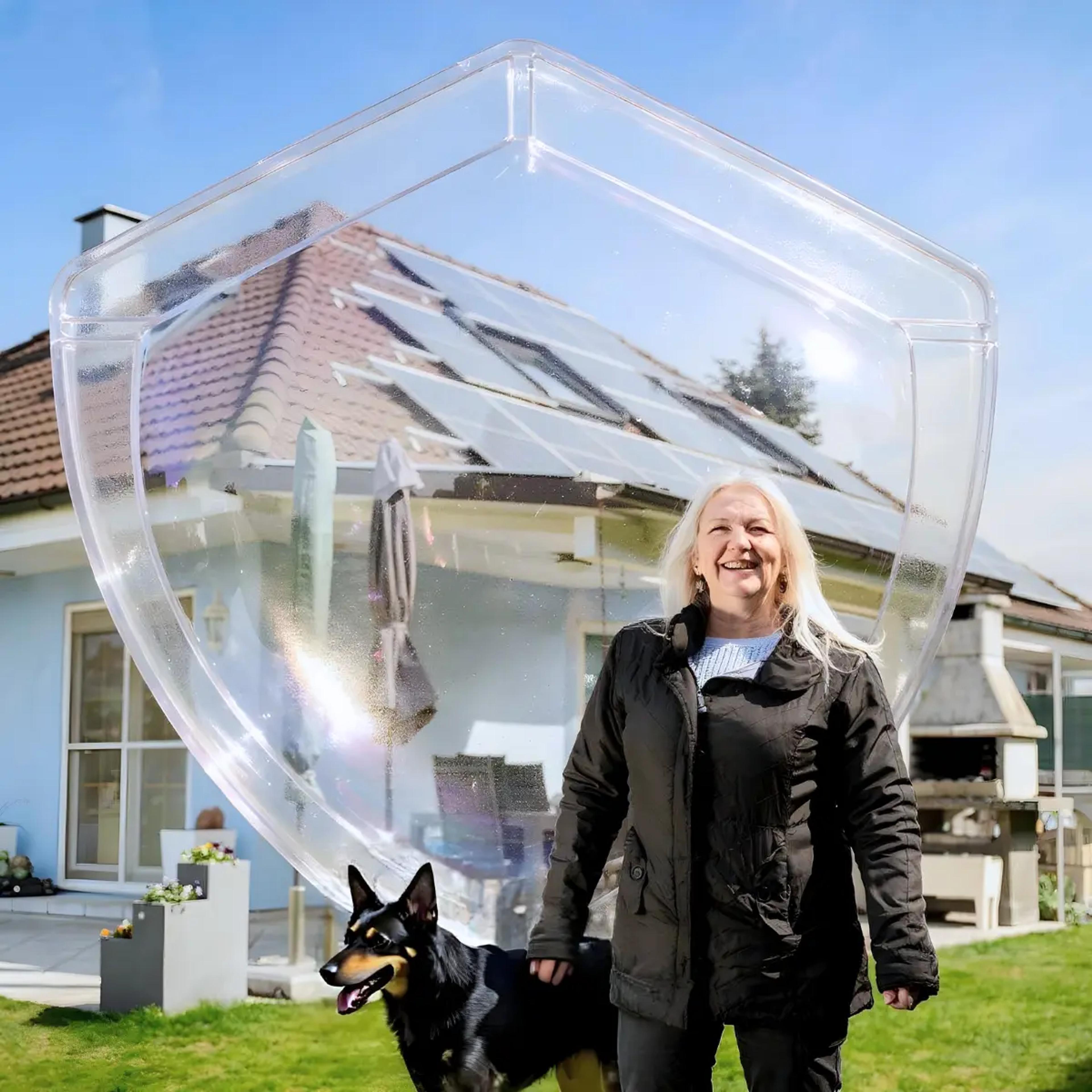 Kobieta z psem na tle domu z instalacją fotowoltaiczną.