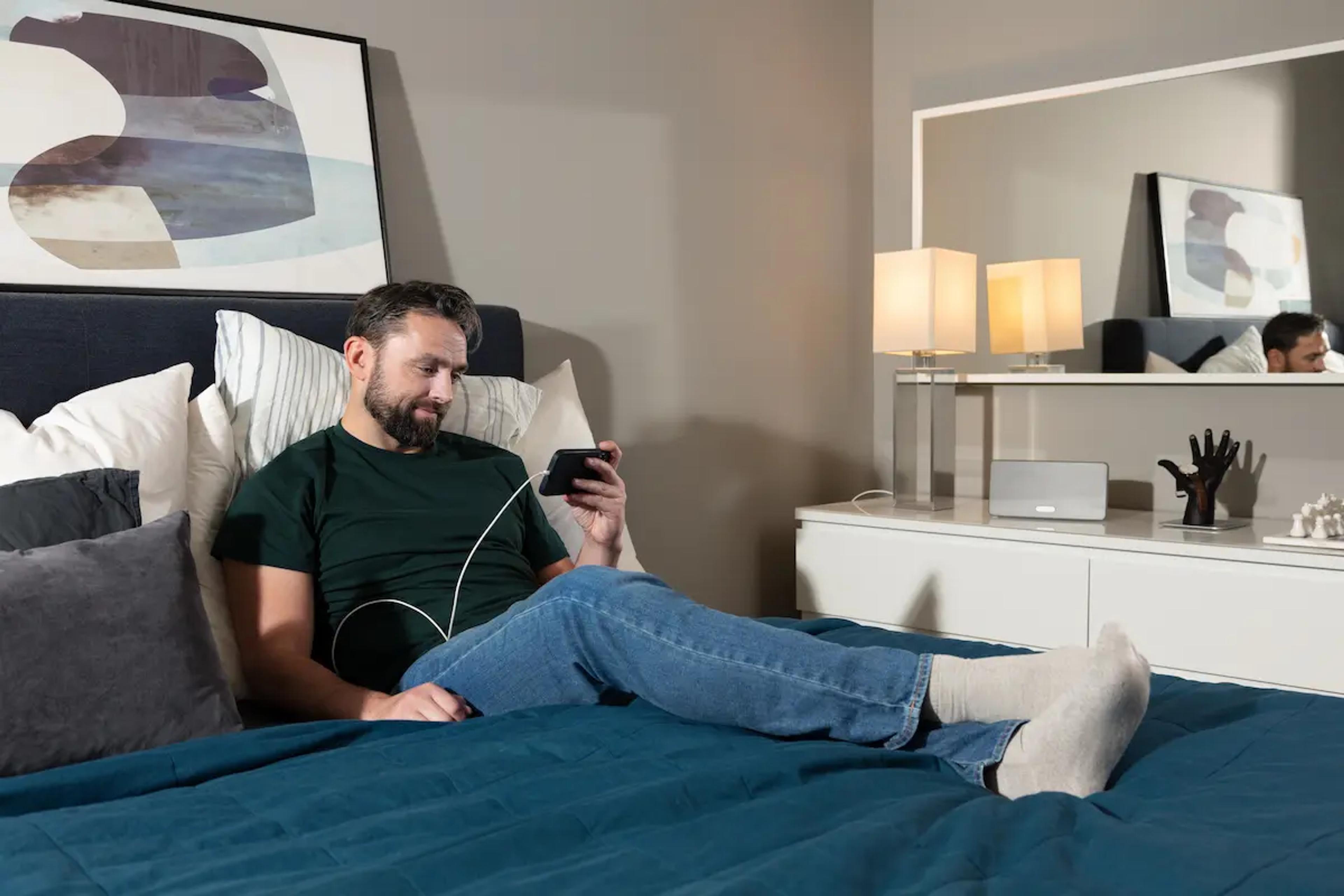 Person liegt im Bett und scrollt auf ihrem Handy