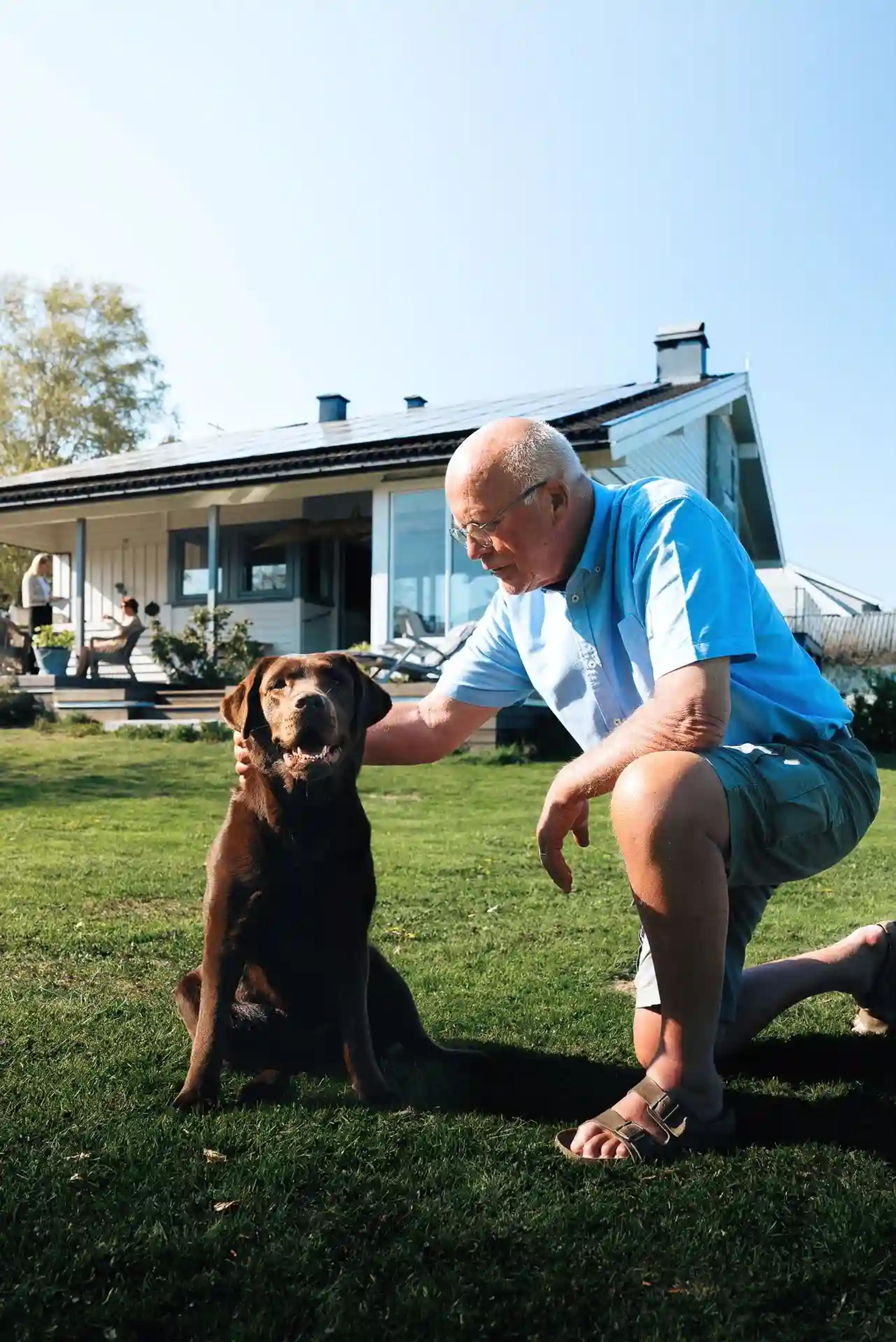 Mann og hund foran hus med solceller på taket 