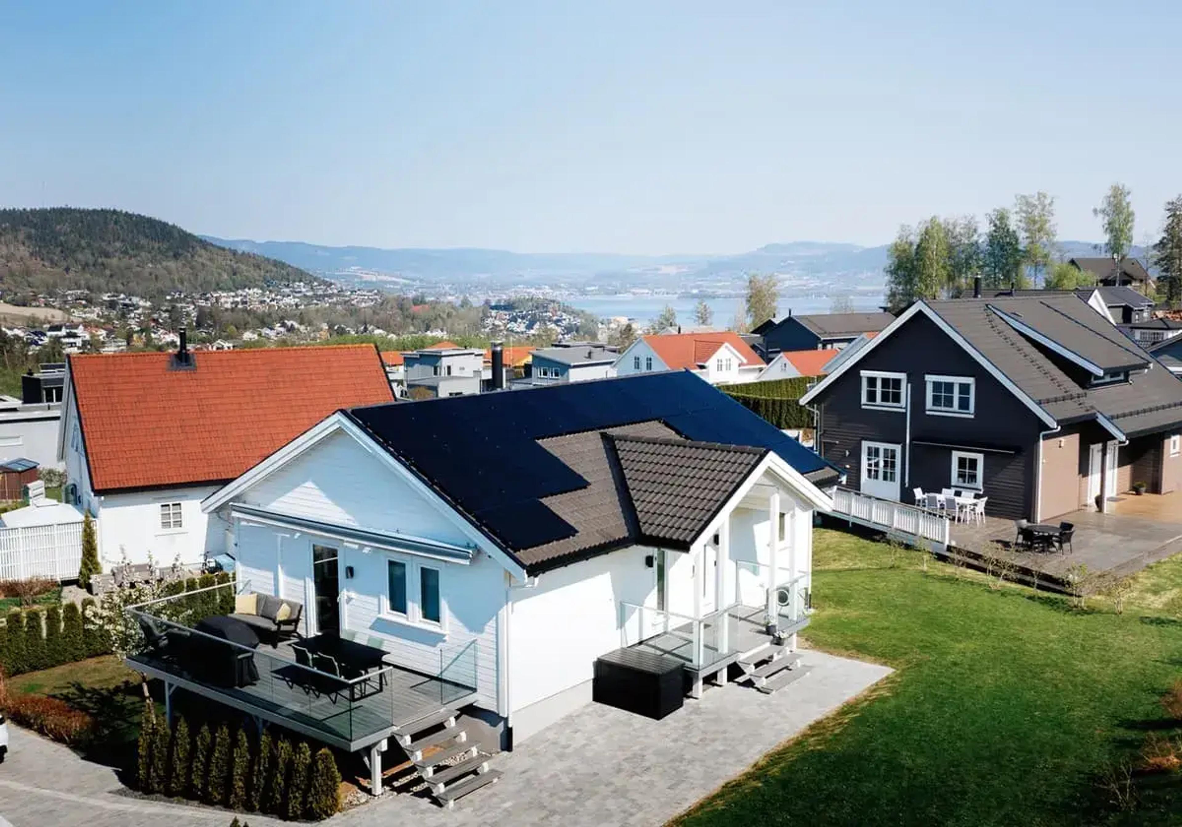 hvit villa i et nabolag med solcellepaneler installert på taket