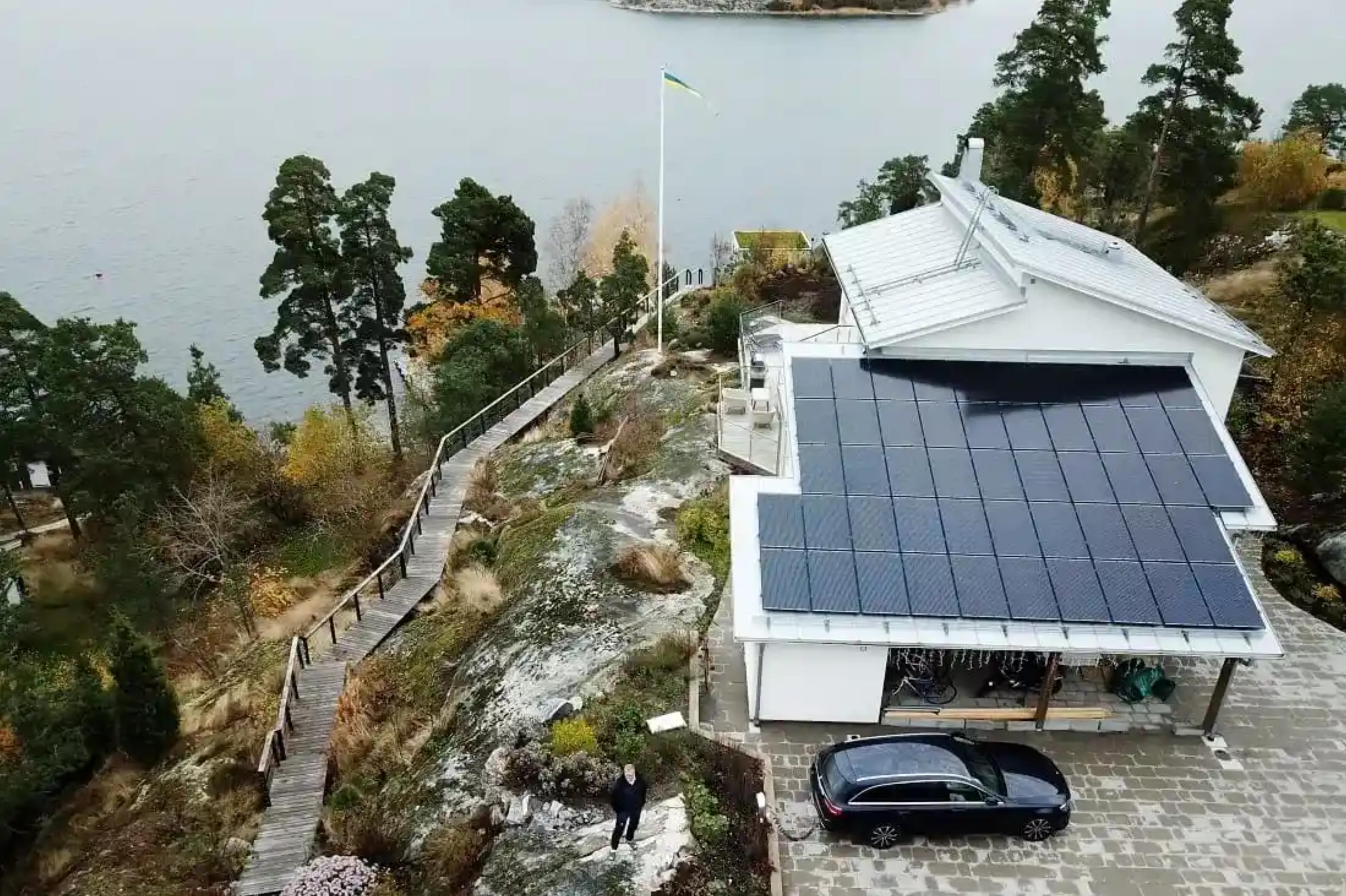 Villa på klippa vid vatten med solceller på taket