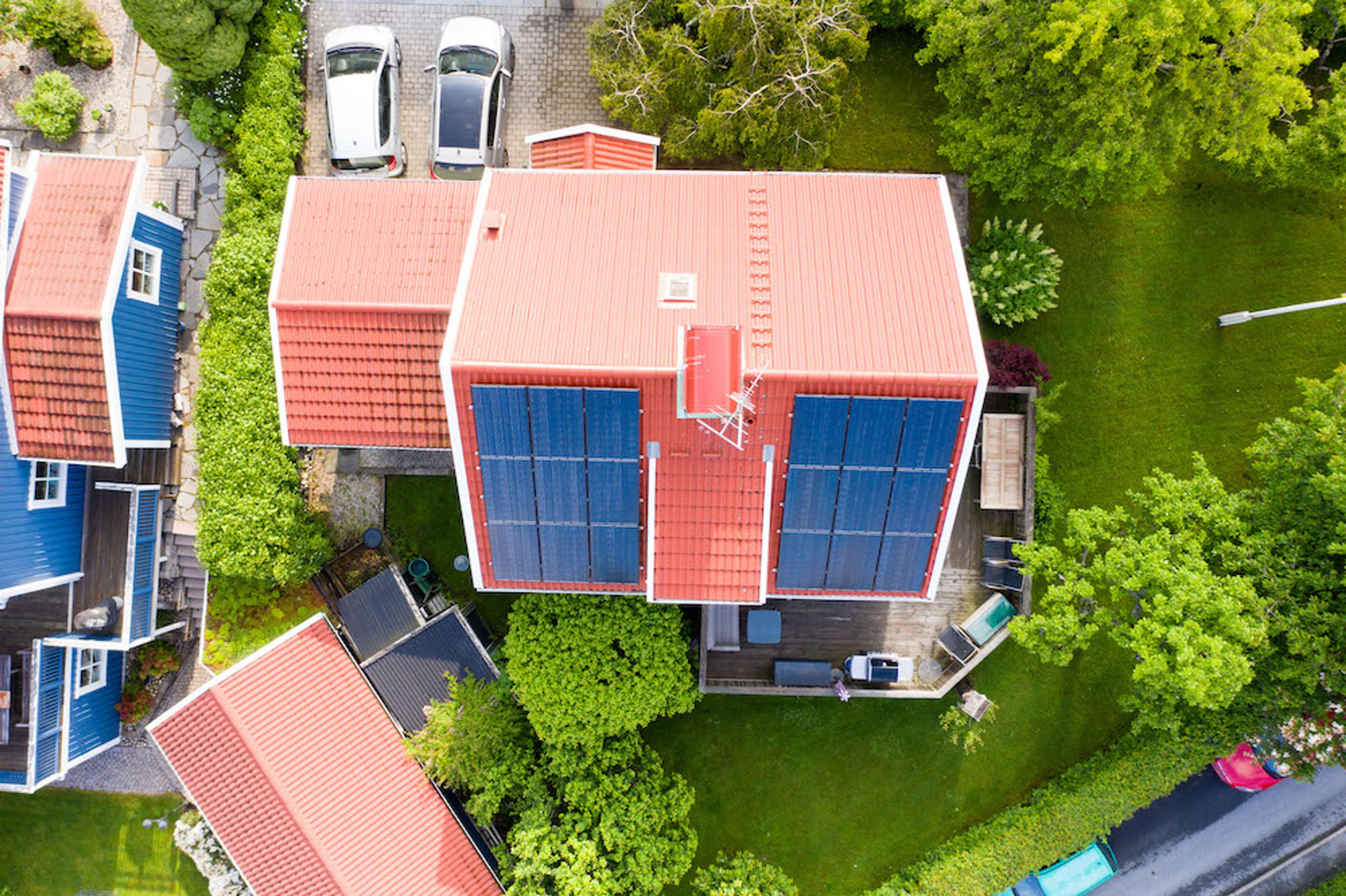 fågelvy över villa med solpaneler och två bilar på garageuppfarten
