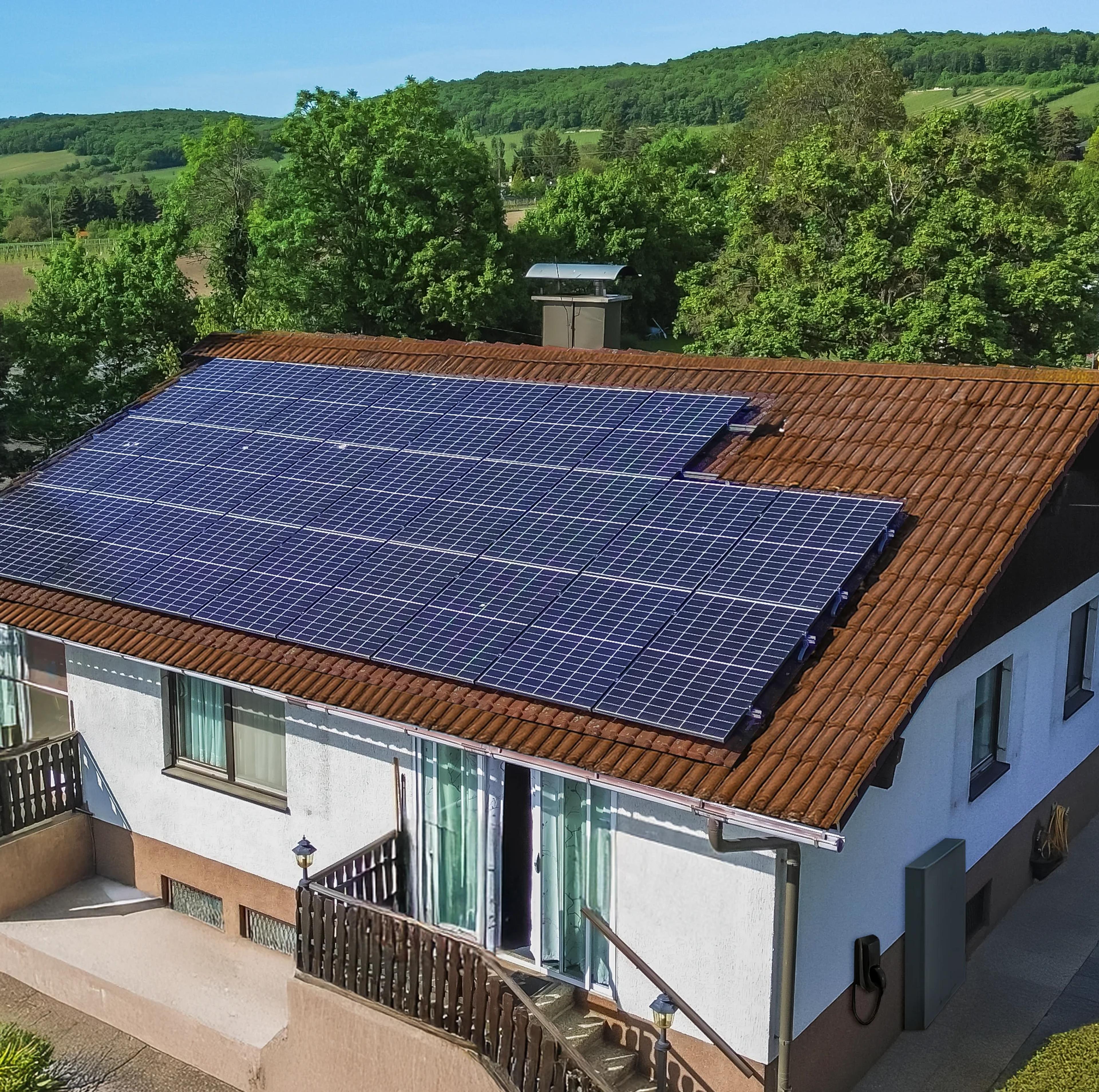 Eine Figur mit Sonne als Kopf mäht den Rasen vor einem Haus mit Solaranlage auf dem Dach.