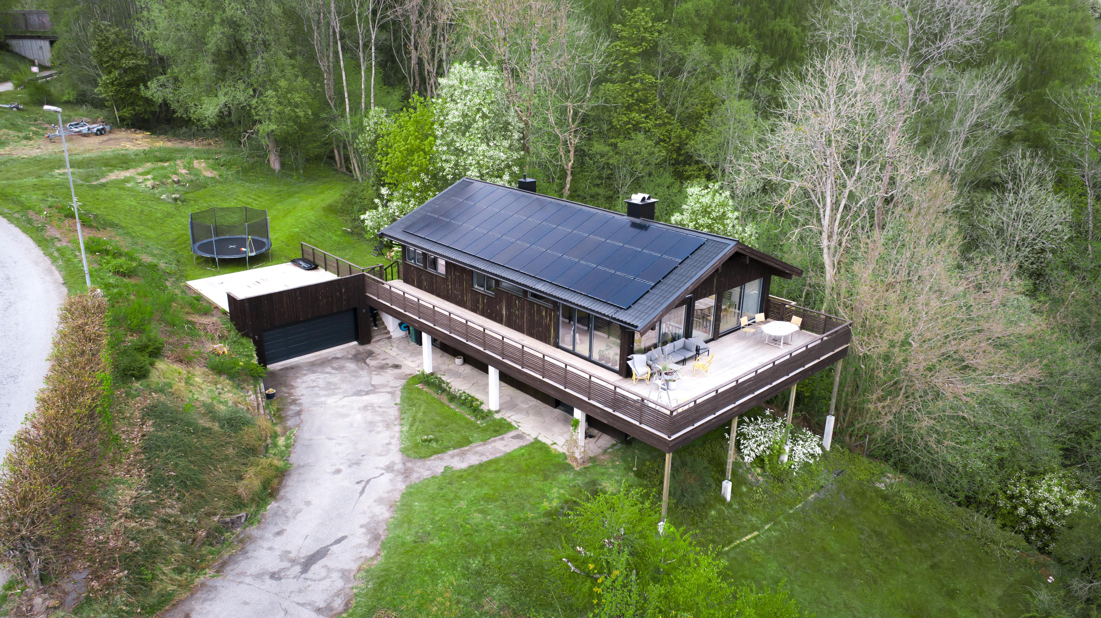 hus med solcellepaneler i grønt landskap