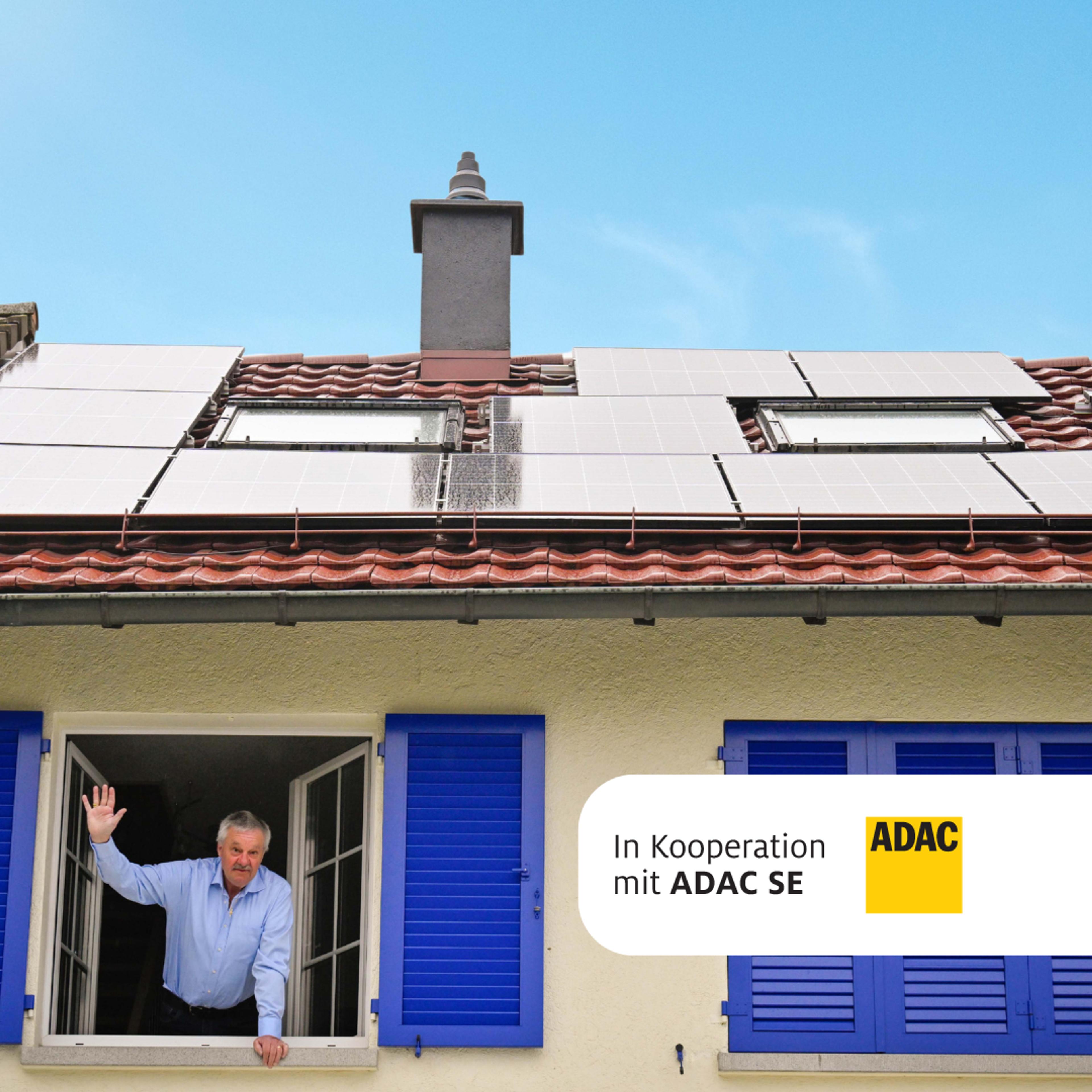 Kunde winkt aus Fenster mit Solaranlage auf dem Dach