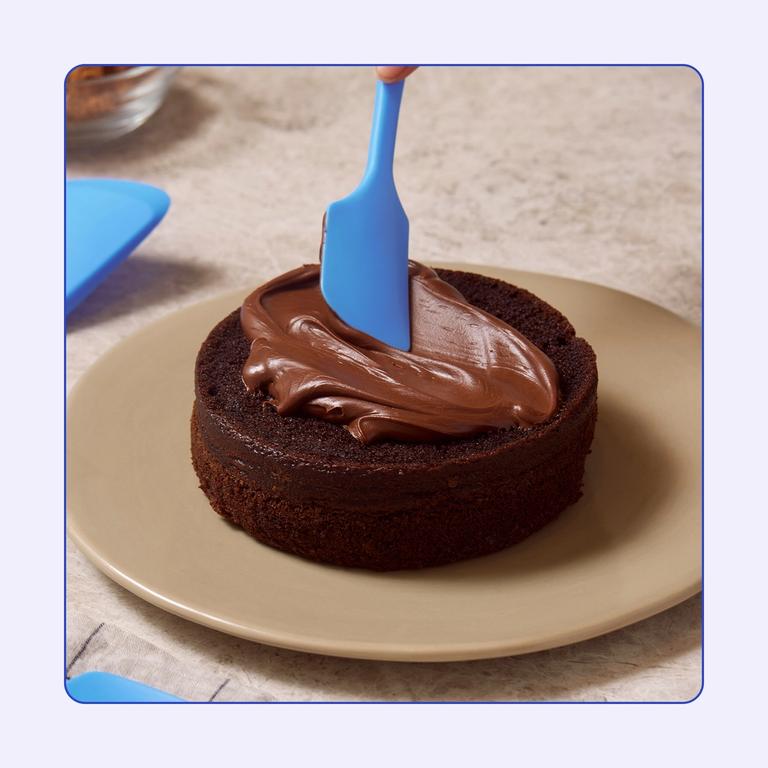 A close up of a Blue Topaz Spatula icing a chocolate cake.