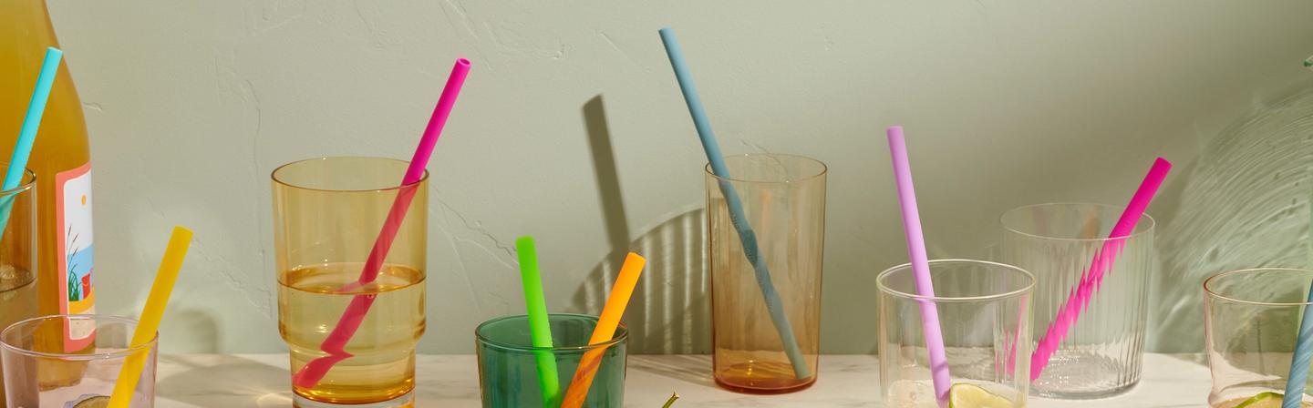 A handful of glass cups with colorful GIR straws placed inside.