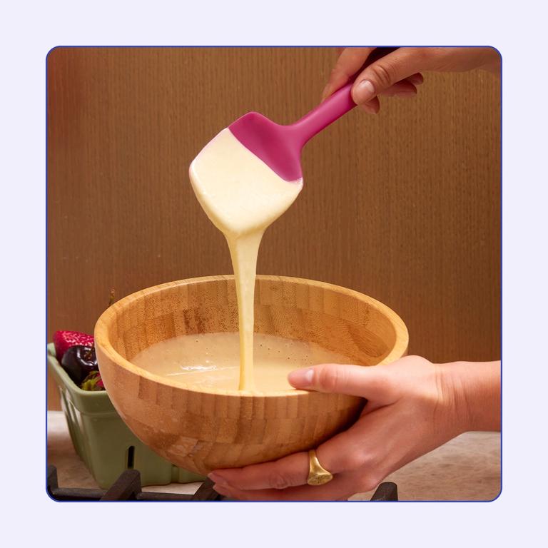 A ruby spoonula scooping cake batter.