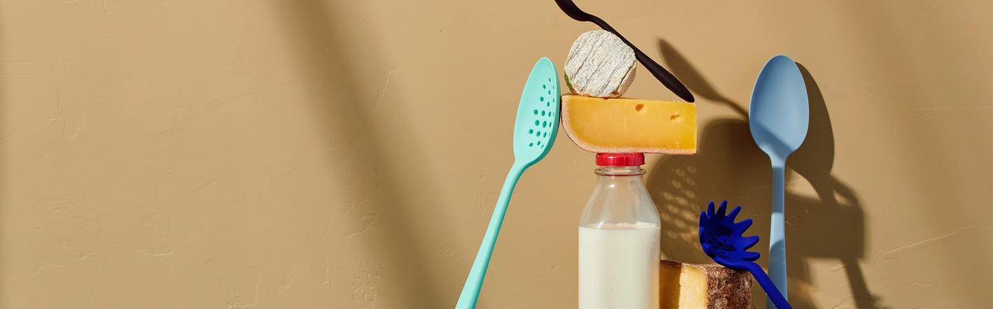 An artistic shot of GIR kitchen tools propped up on cheese blocks and a dairy container.