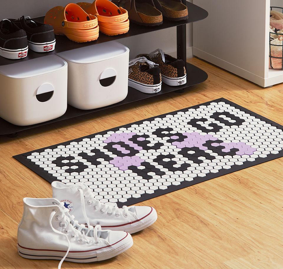 A lifestyle image of the tile mat and entryway rack with assorted bins and shoes.